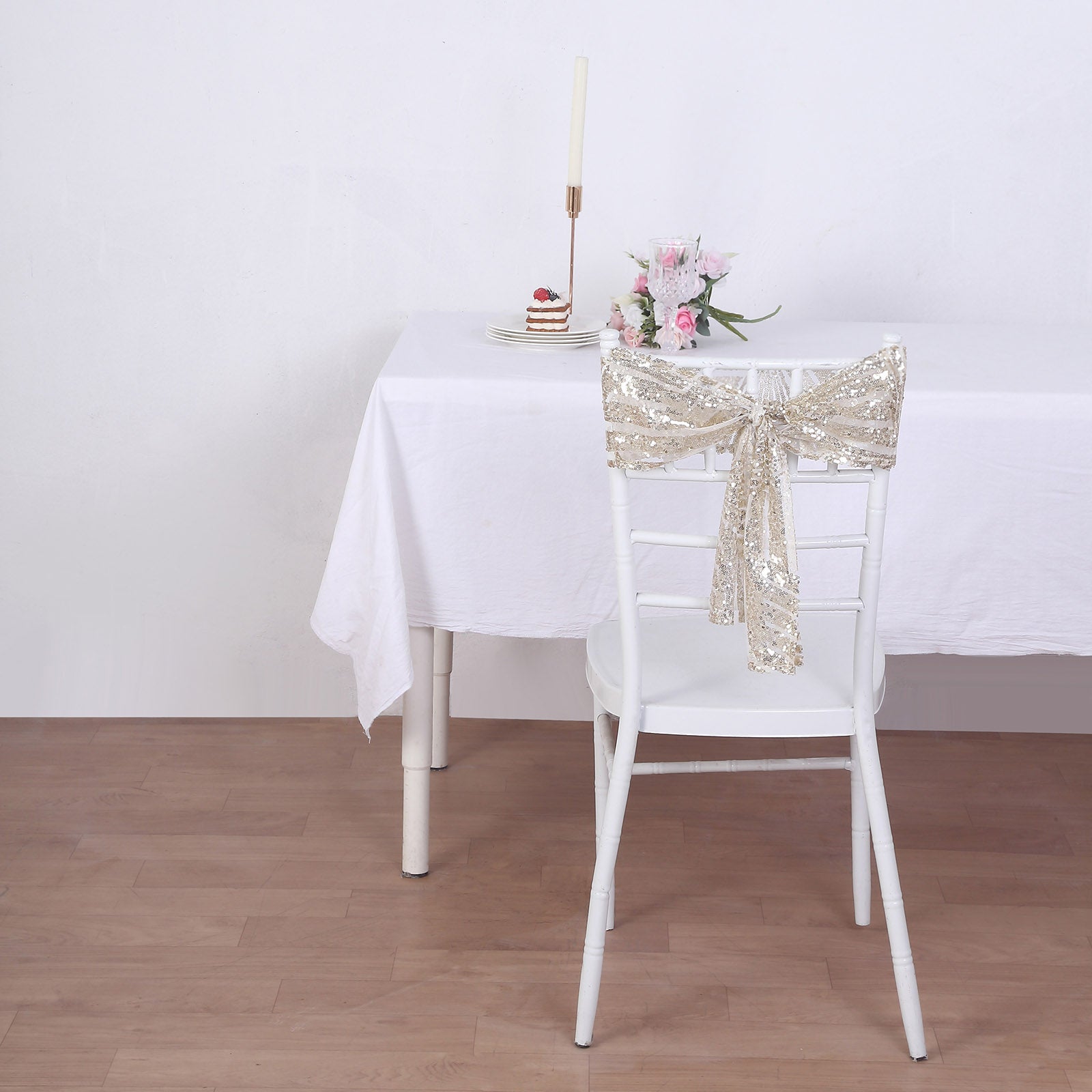 Champagne sequin chair sash on a white chair at a decorated table.