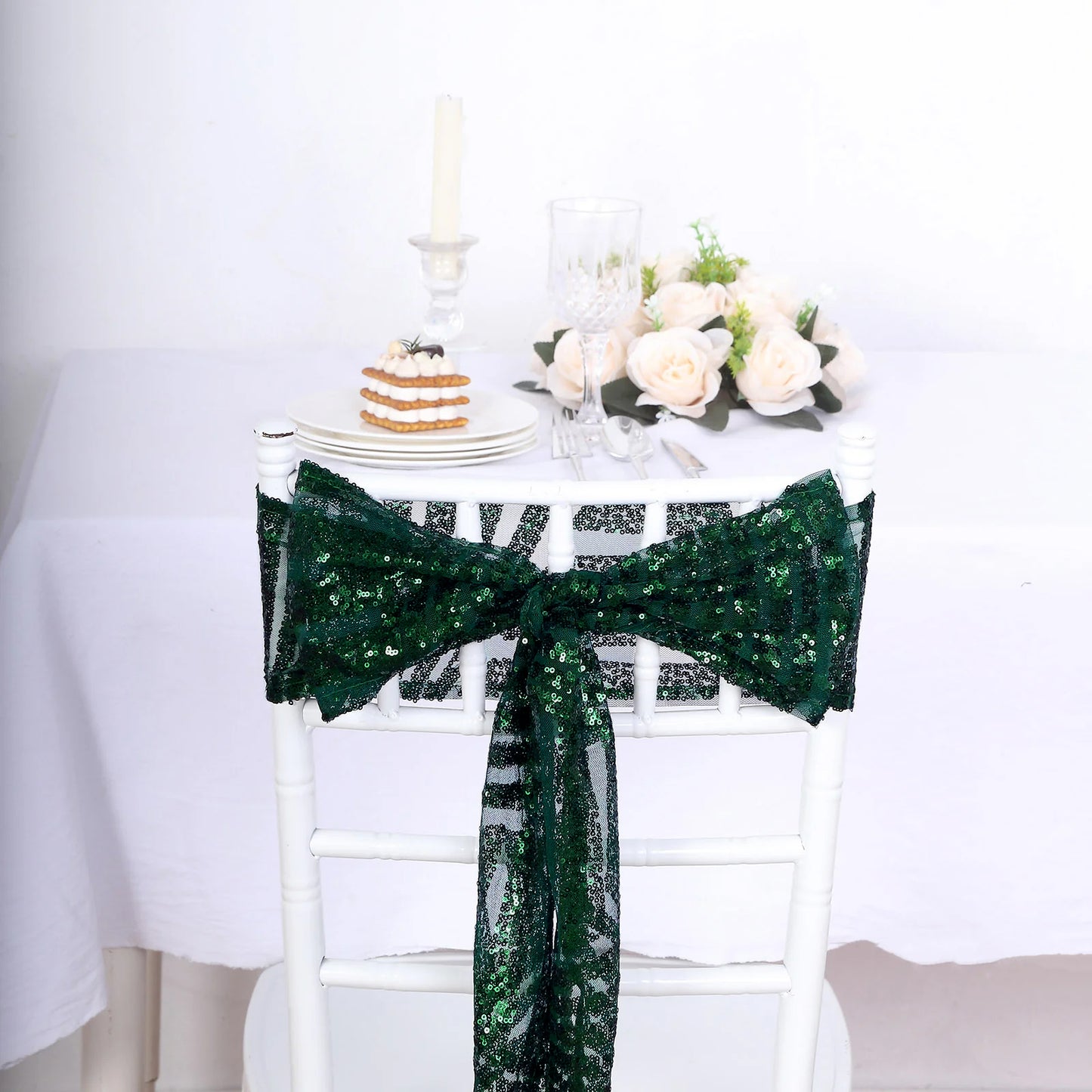 Emerald green sequin chair sash tied on a white chair.