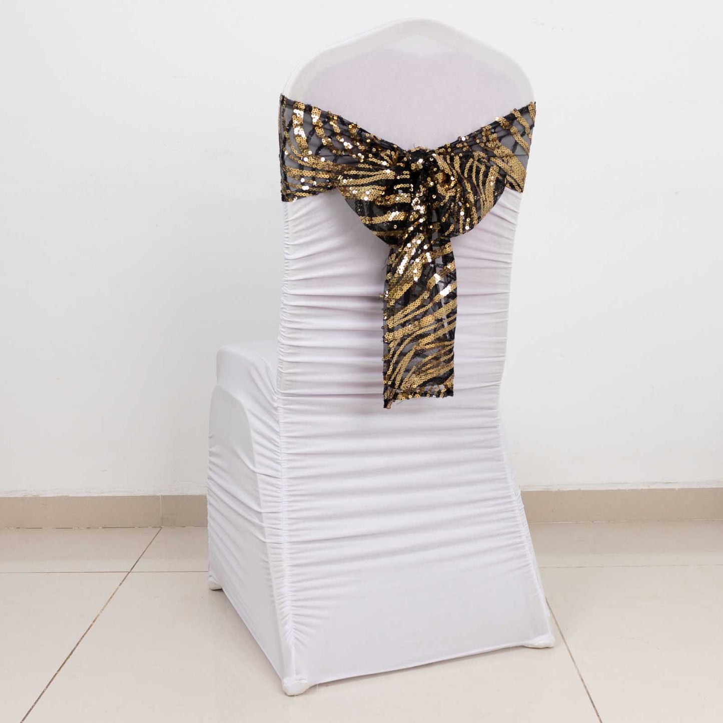 Black gold wave embroidered sequin mesh chair sash on a white chair.