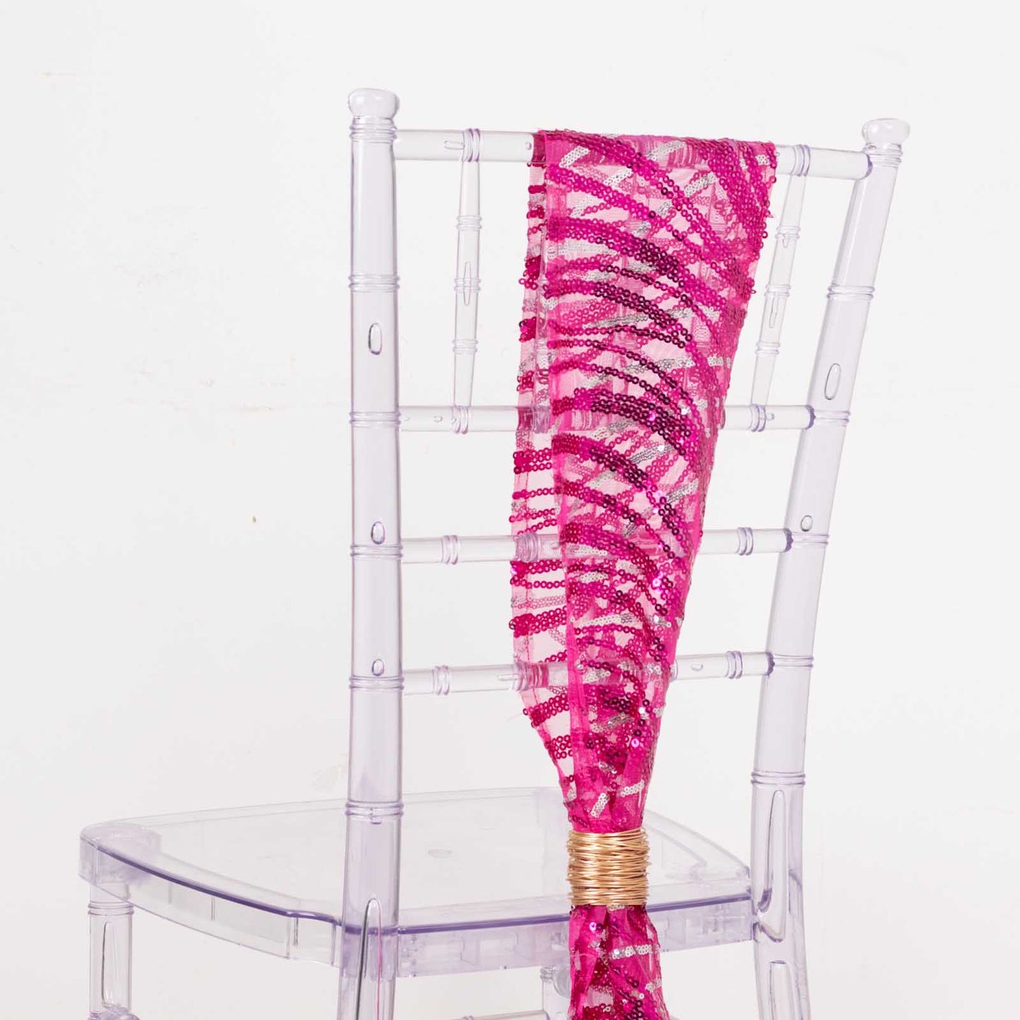 Fuchsia silver wave embroidered sequin mesh chair sash on a clear chair.