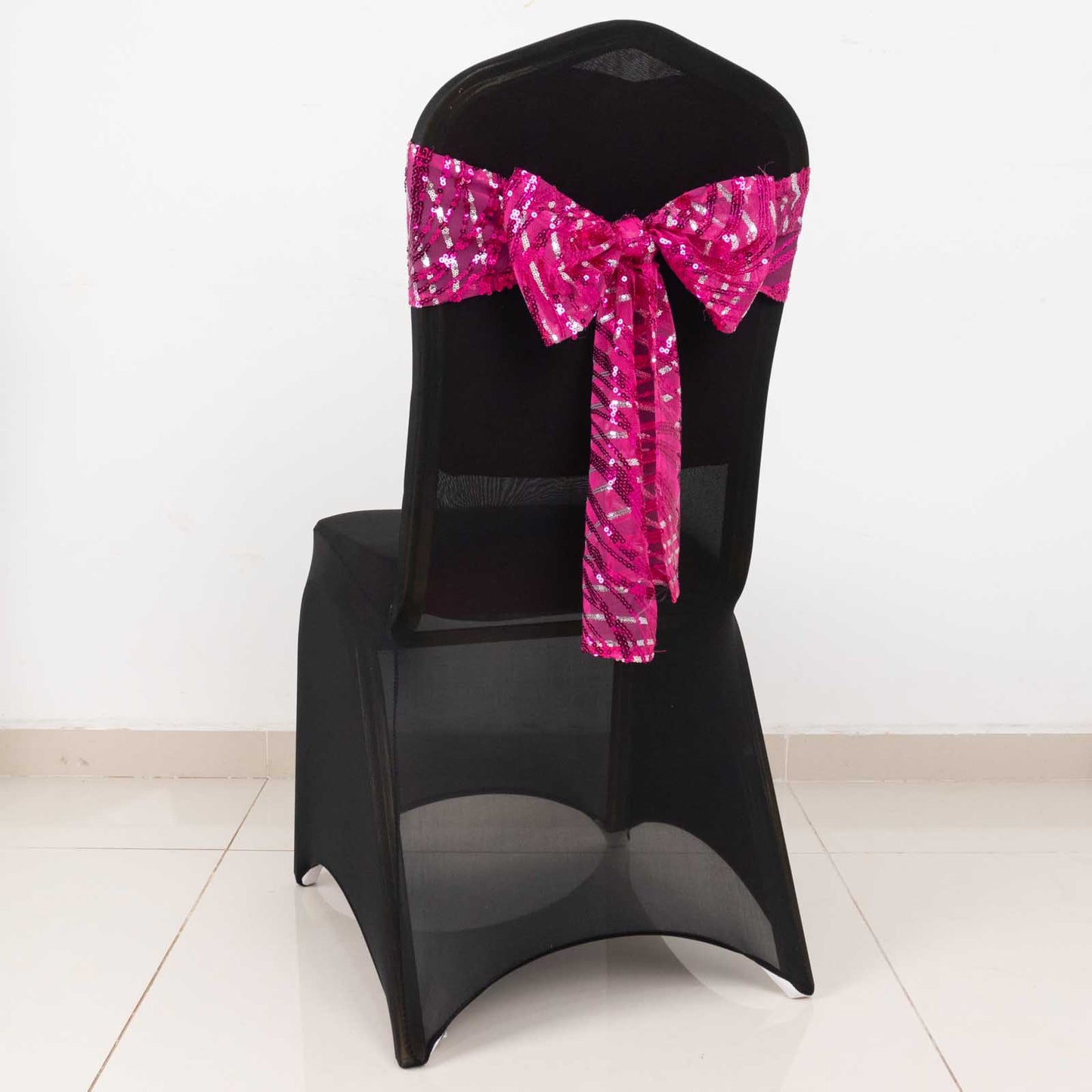 Fuchsia sequin mesh chair sash with wave embroidery on a black chair.