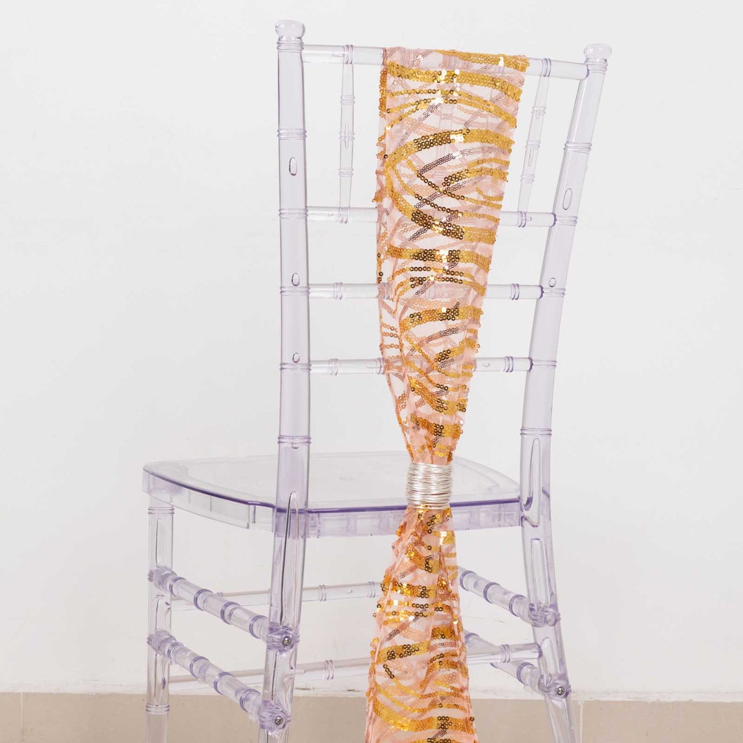 Rose gold mesh chair sash with gold wave sequins on a clear chair.