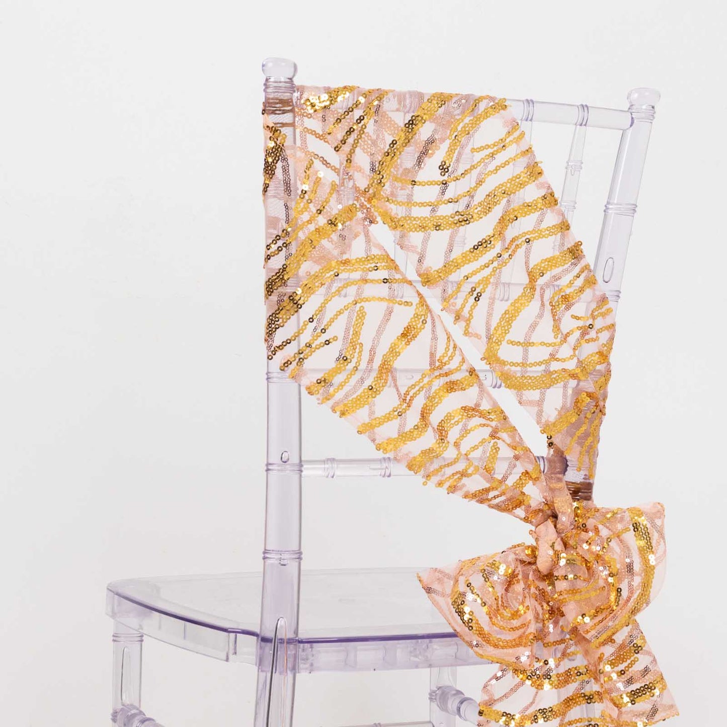 Rose gold mesh chair sash with gold wave sequins on a clear chair.