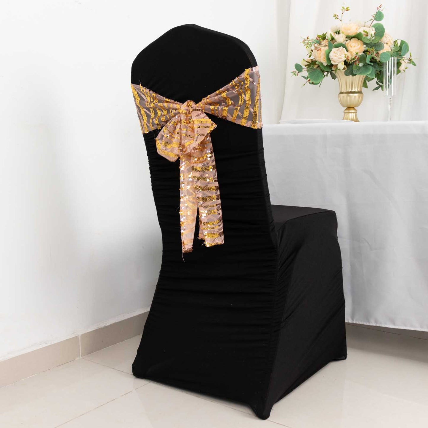 Rose gold mesh chair sash with gold wave sequins on a black chair.