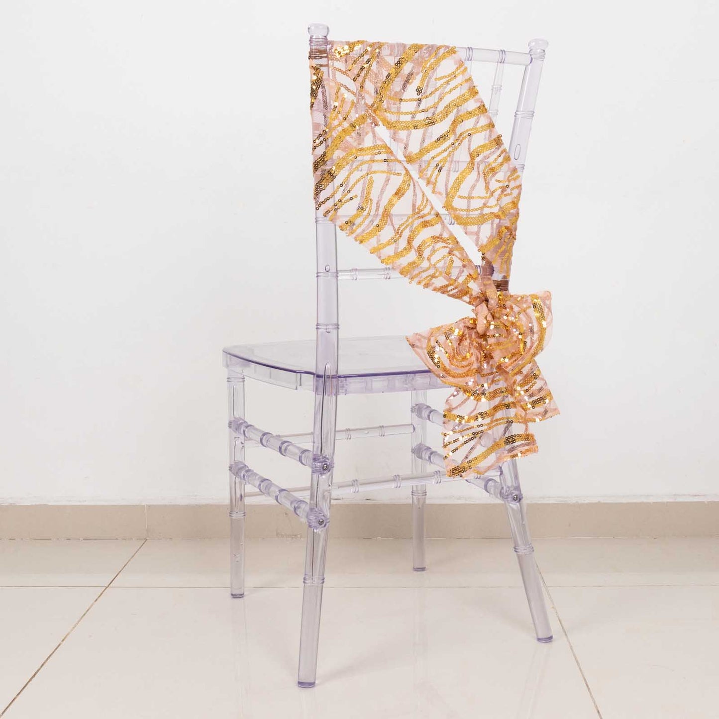 Rose gold mesh chair sash with gold wave sequins on a clear chair.
