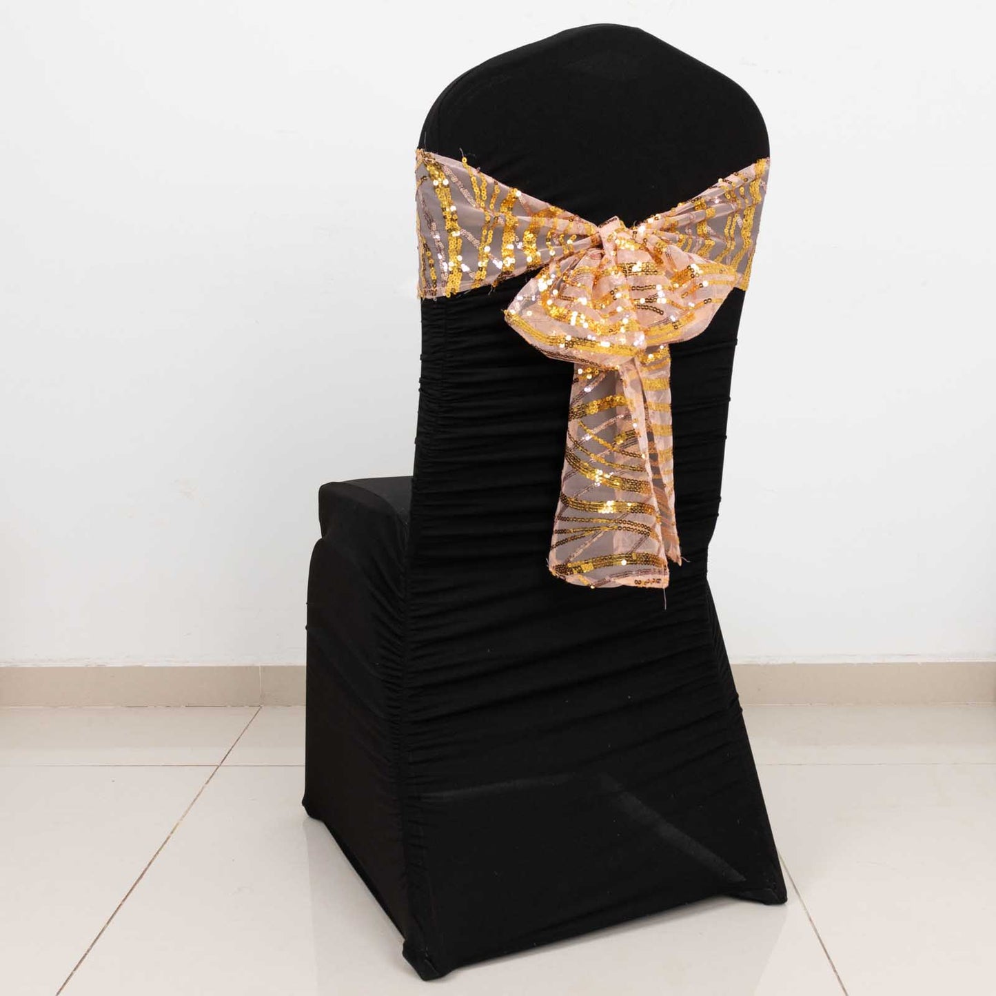 Rose gold mesh chair sash with gold sequins on a black chair.