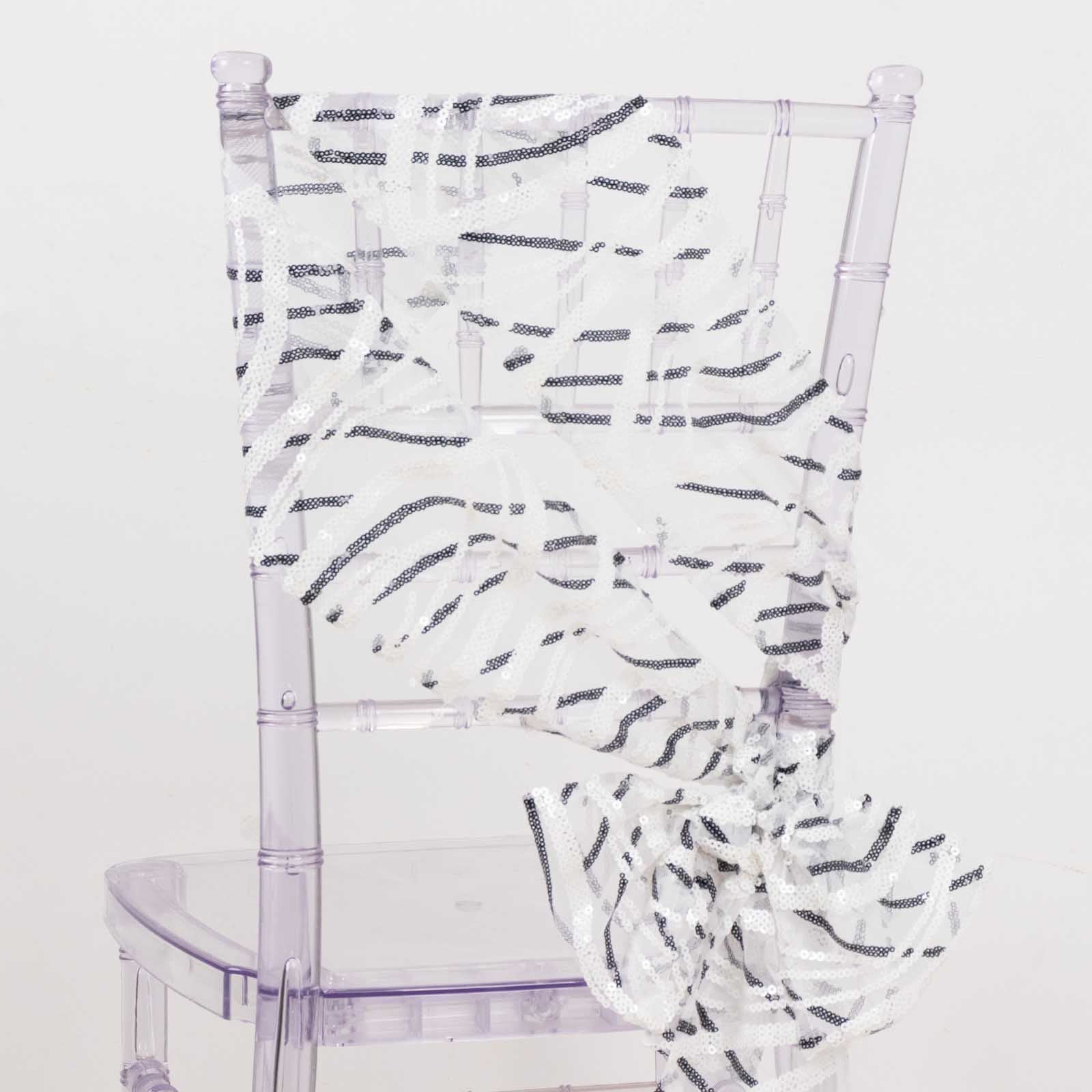 White and black wave embroidered sequin mesh chair sash on a clear chair.