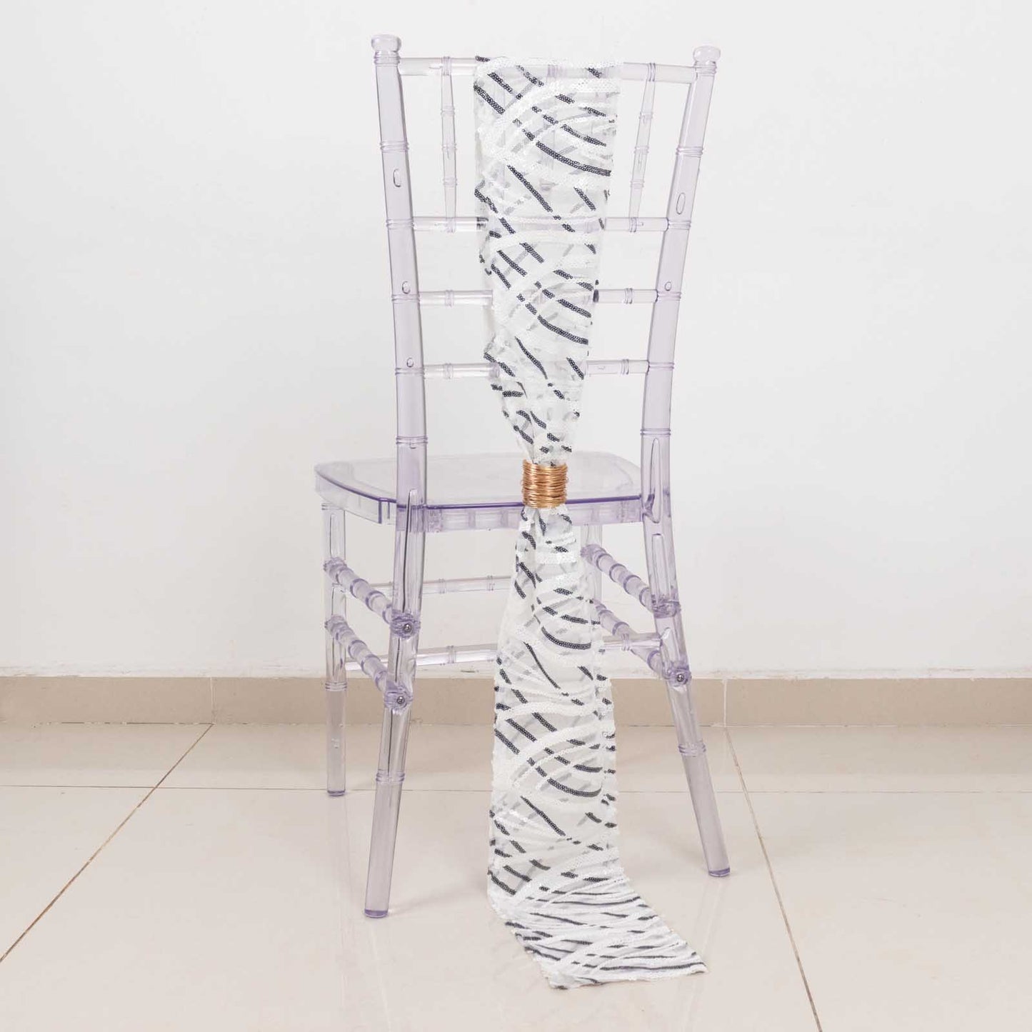 White and black wave embroidered sequin mesh chair sash on a clear chair.