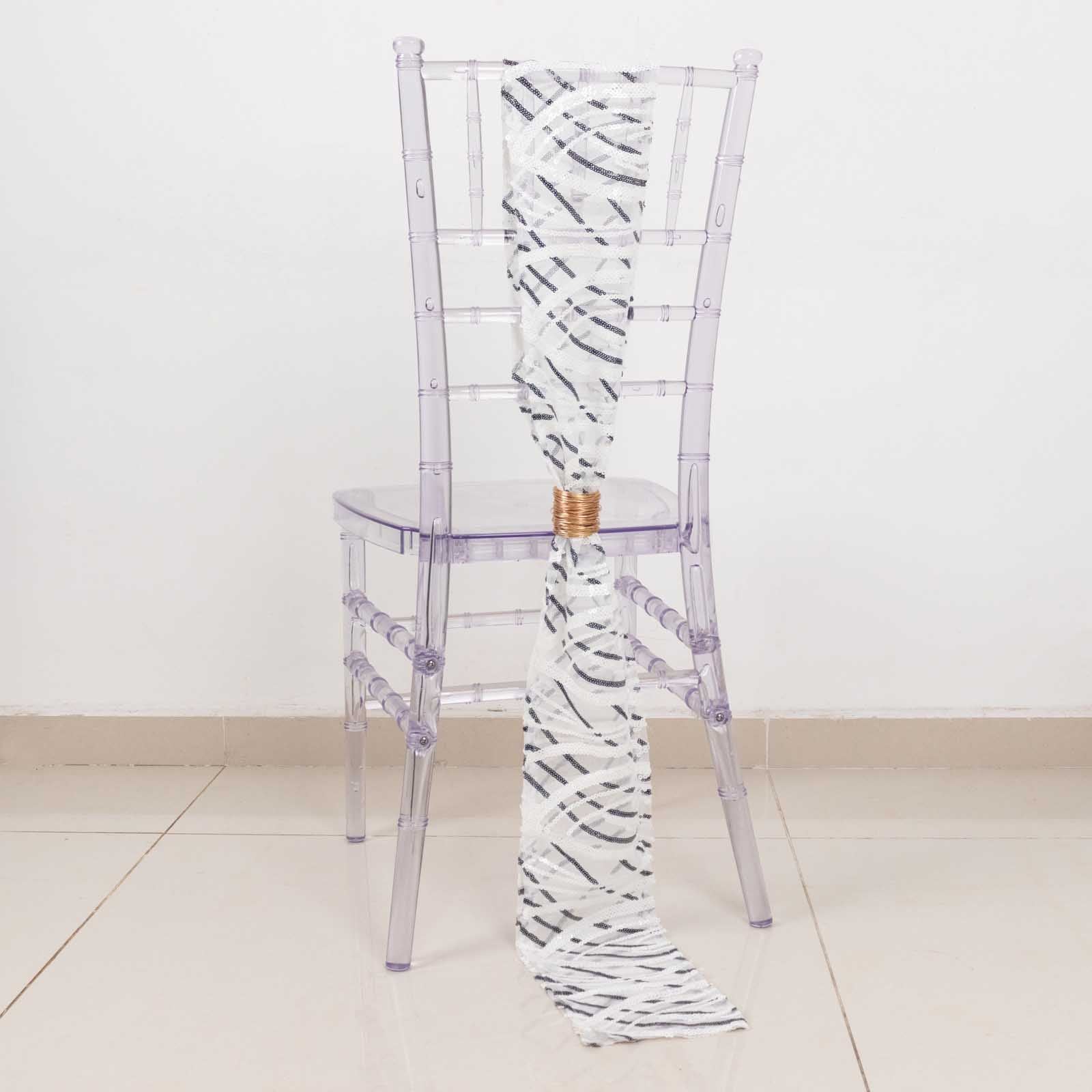 White and black wave embroidered sequin mesh chair sash on a clear chair.