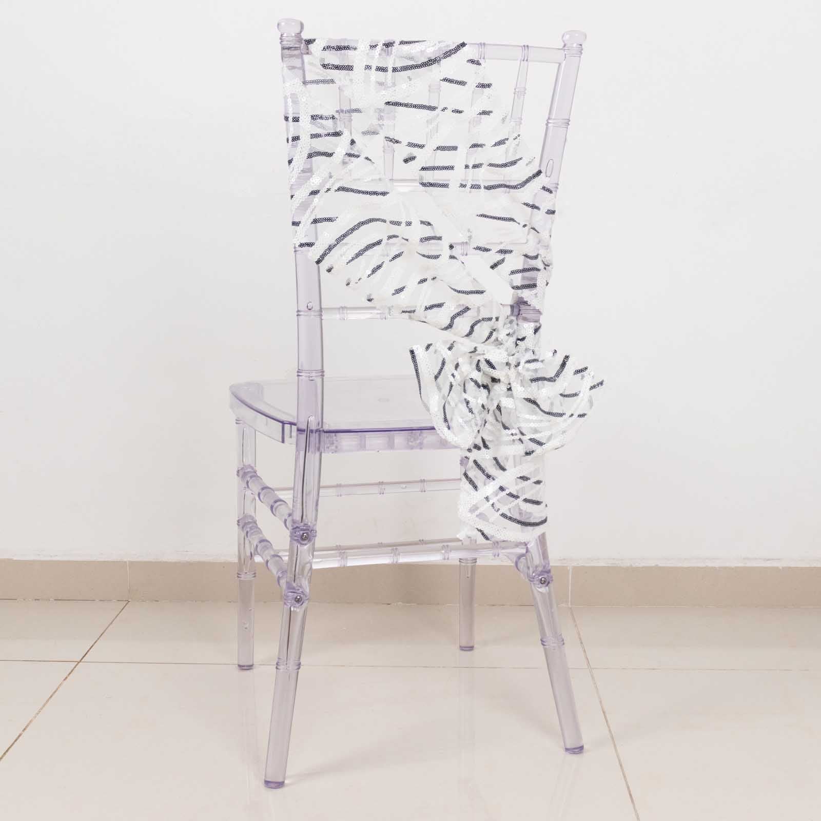 White and black wave embroidered sequin chair sash on a clear chair.