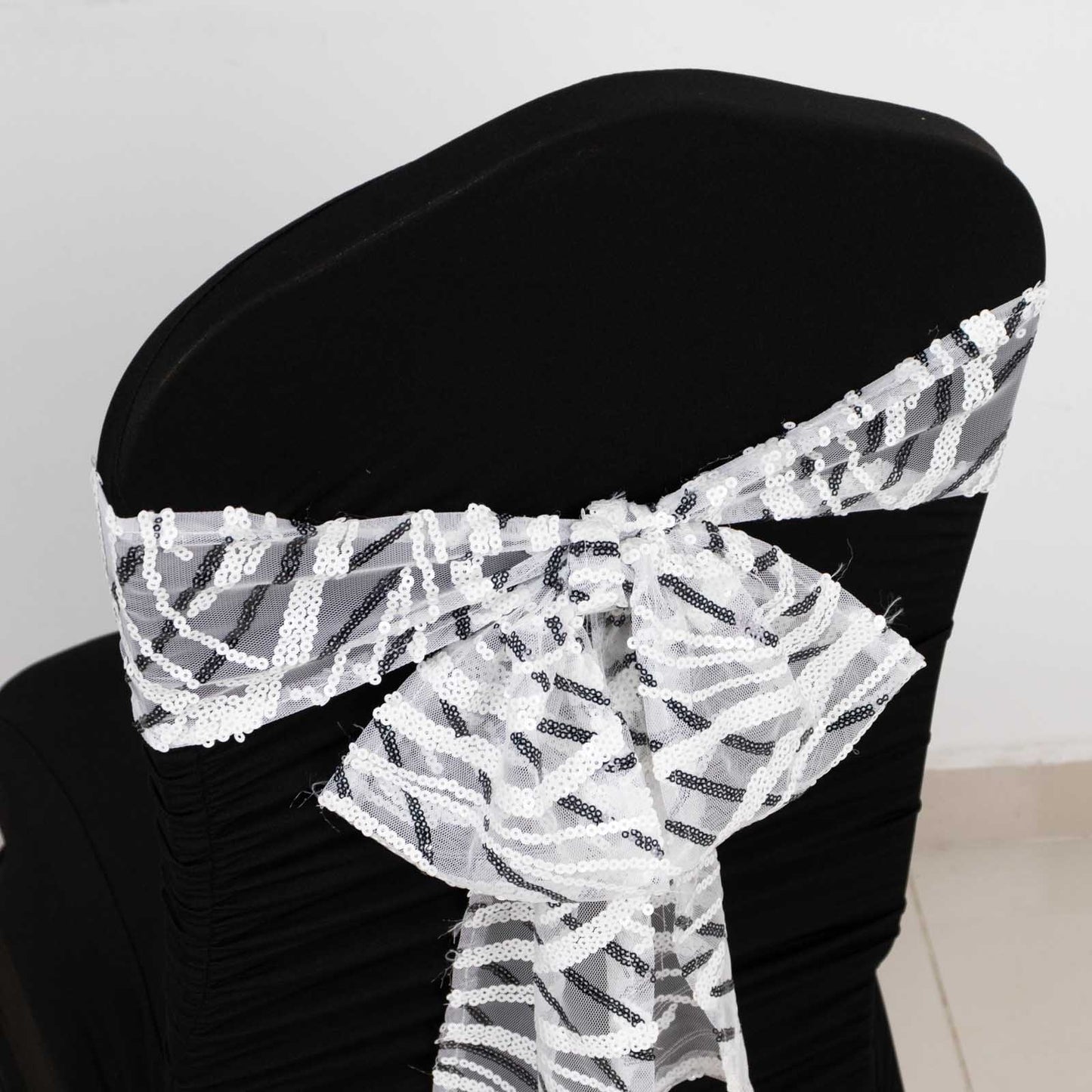 White and black wave embroidered sequin chair sash on a black chair.