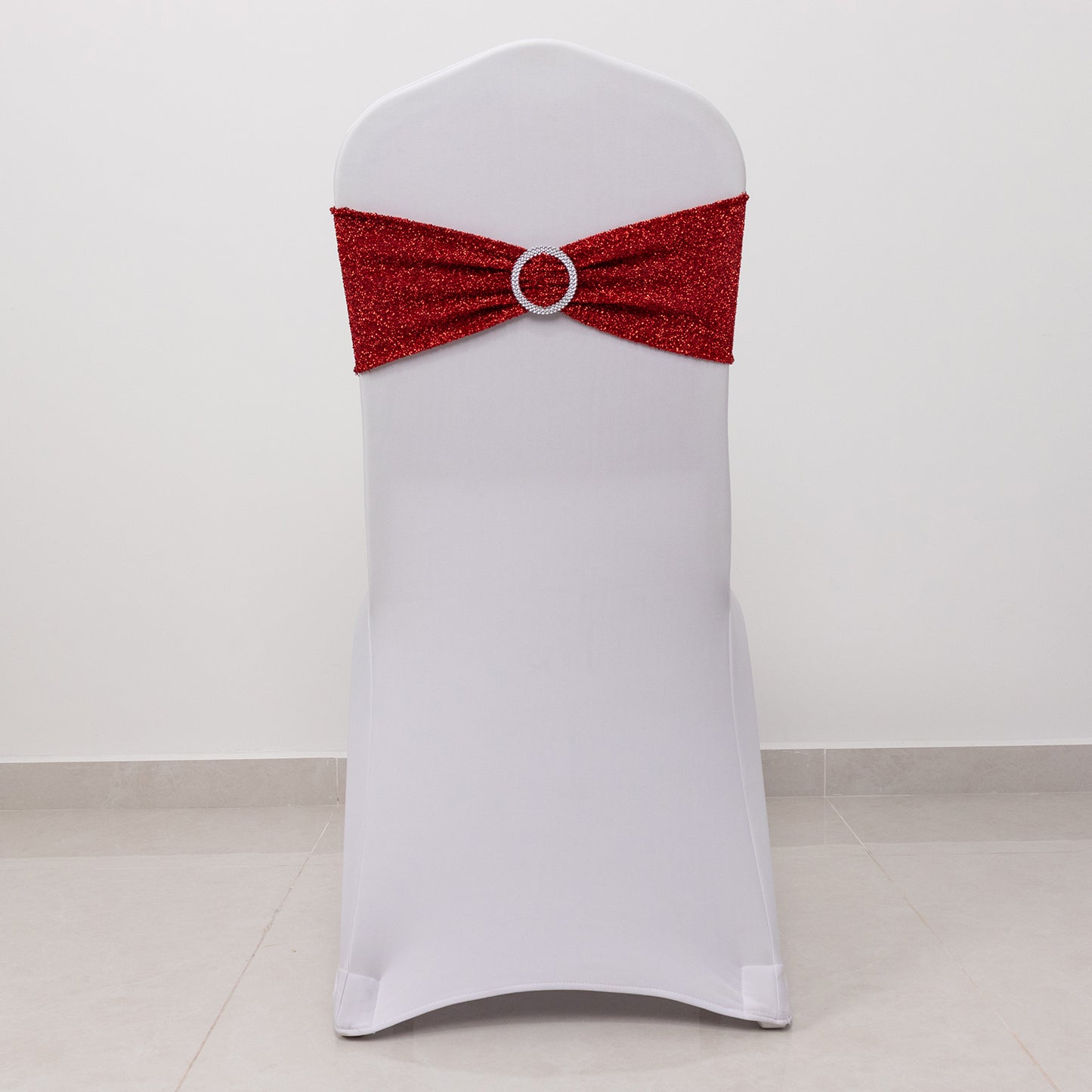 Red shimmer tinsel spandex chair sash with silver rhinestone buckle on a white chair.