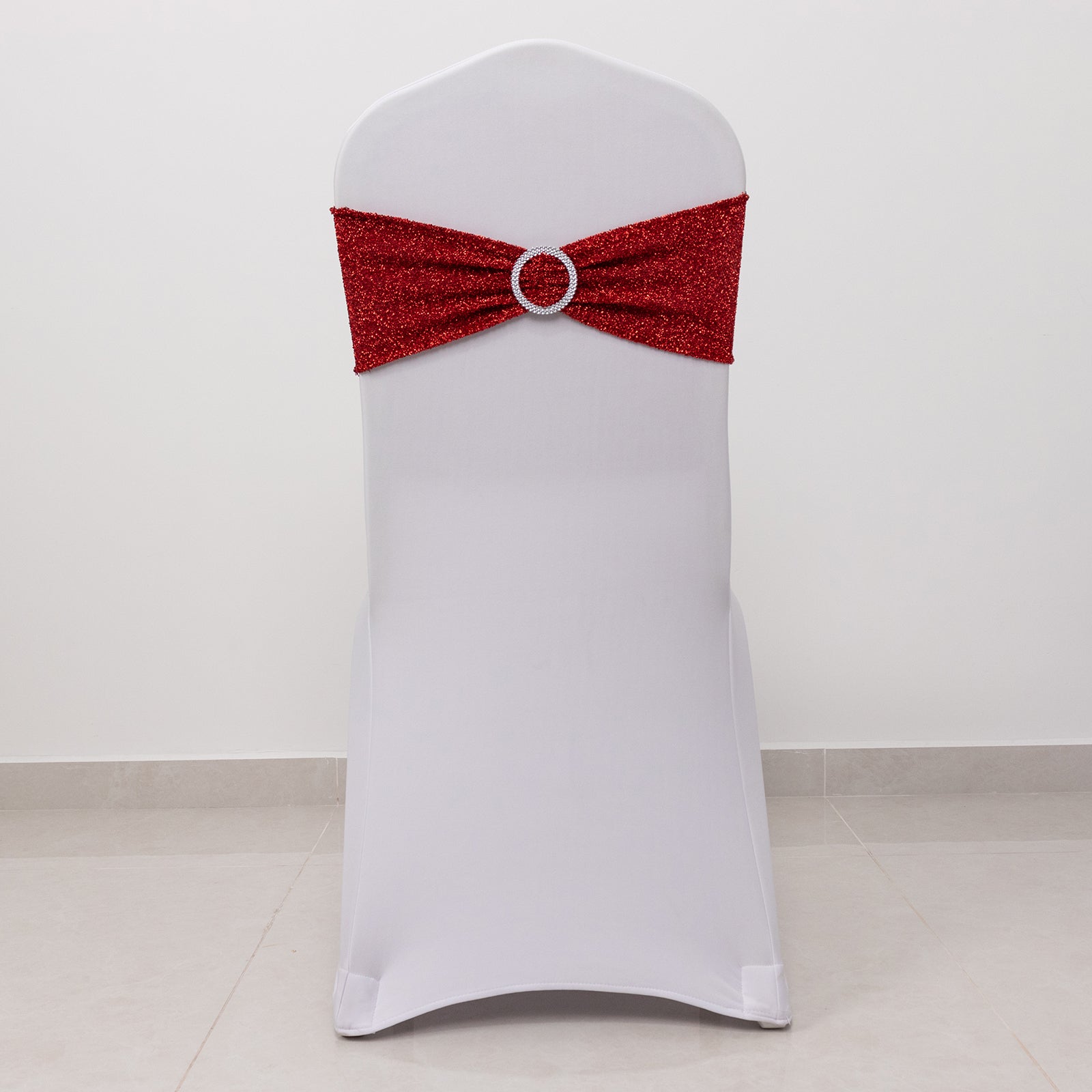 Red shimmer tinsel spandex chair sash with silver rhinestone buckle on a white chair.