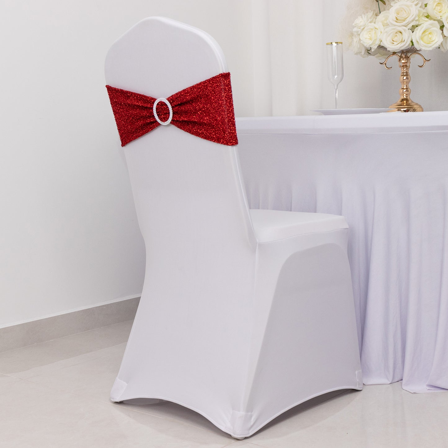 Red shimmer tinsel spandex chair sash with silver rhinestone buckle on white chair.
