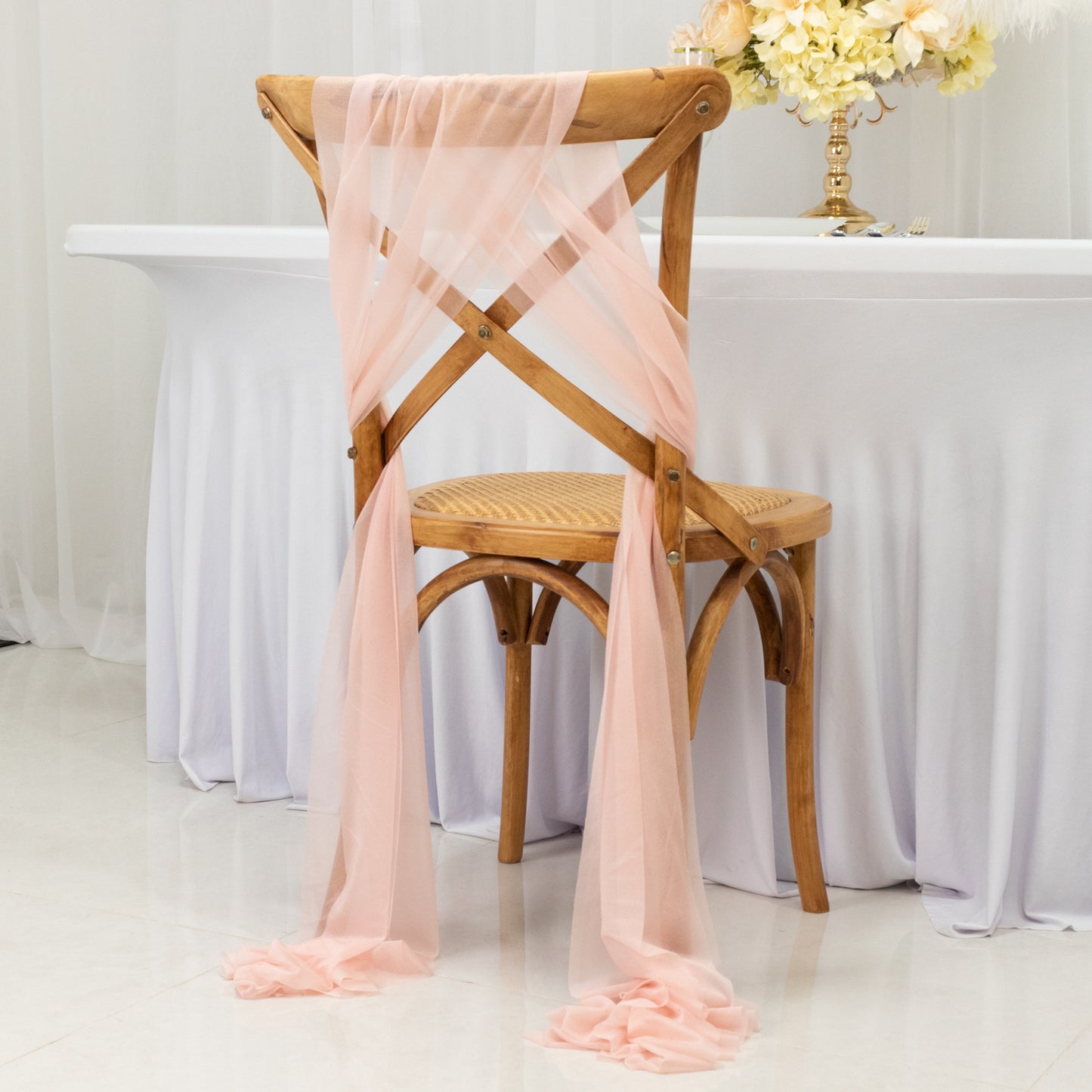 Blush sheer chair drape decor elegantly styled on a wooden chair.