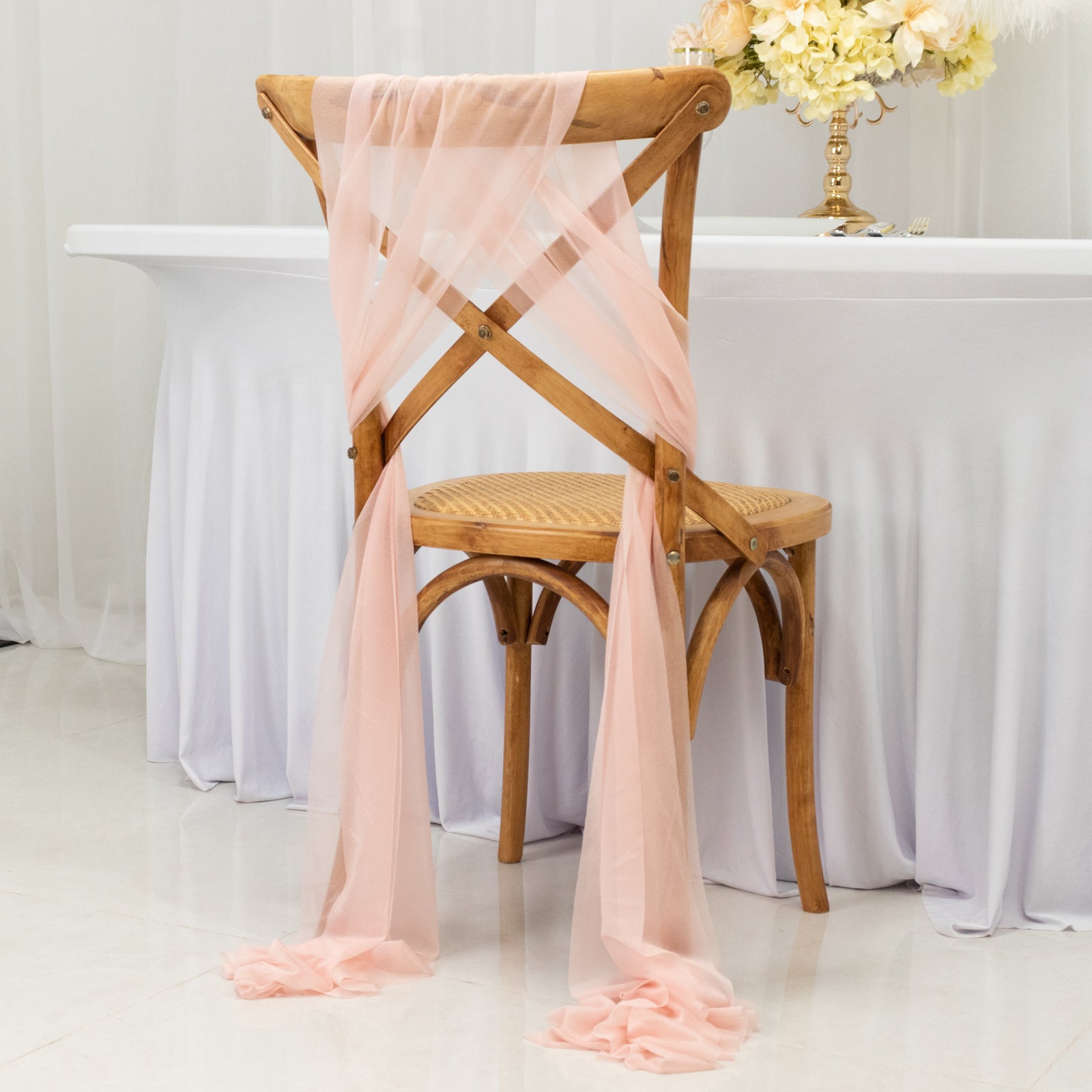 Blush sheer chair drape decor elegantly styled on a wooden chair.