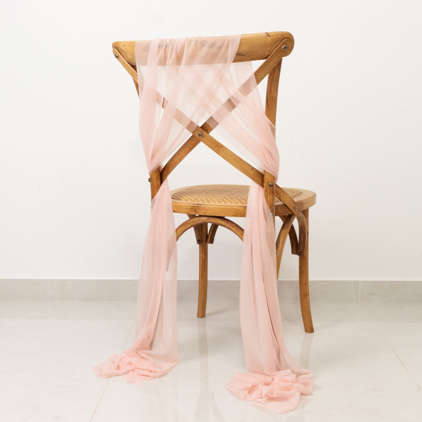 Blush sheer chair drape decor elegantly styled on a wooden chair.