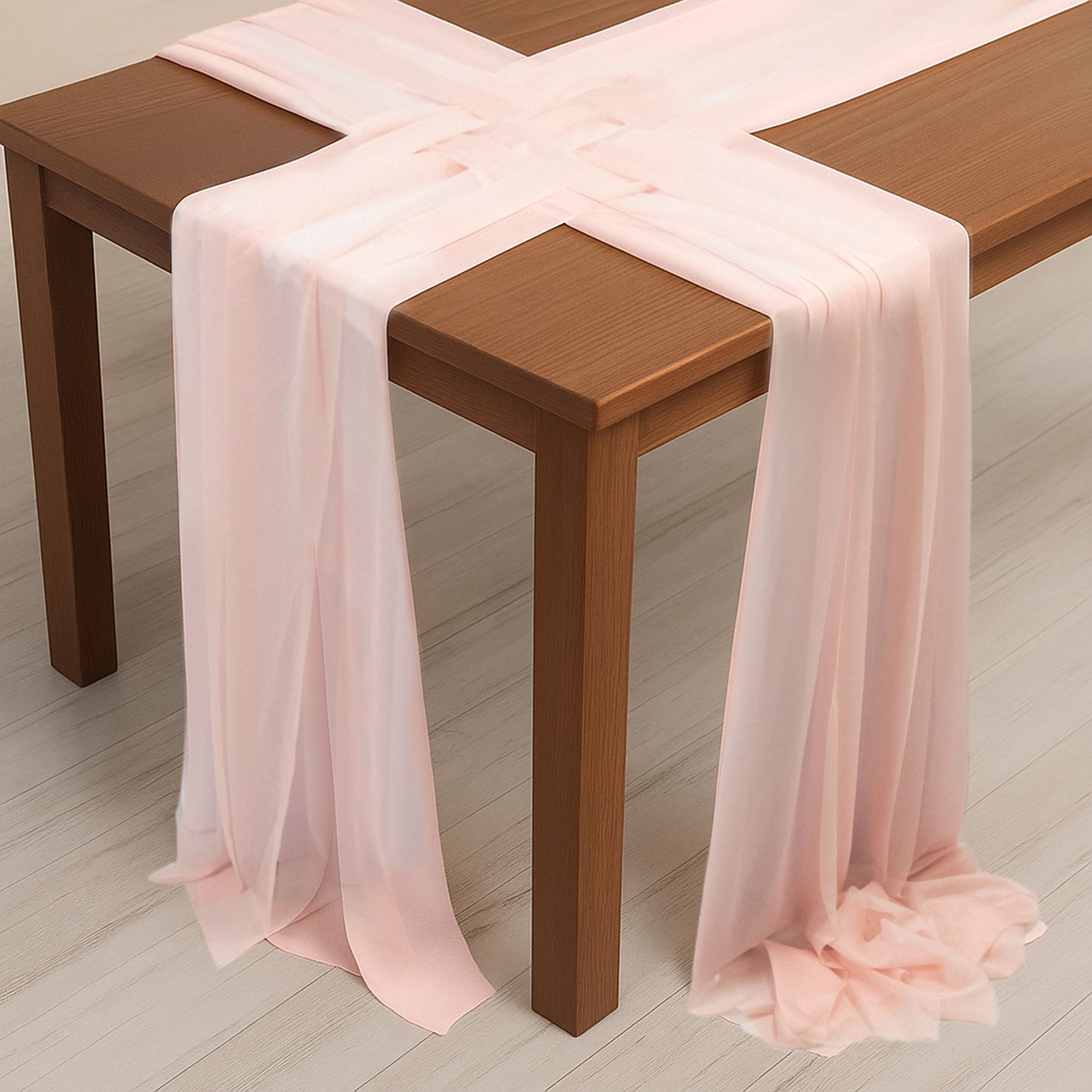 Blush sheer table runners draped elegantly over a wooden table.