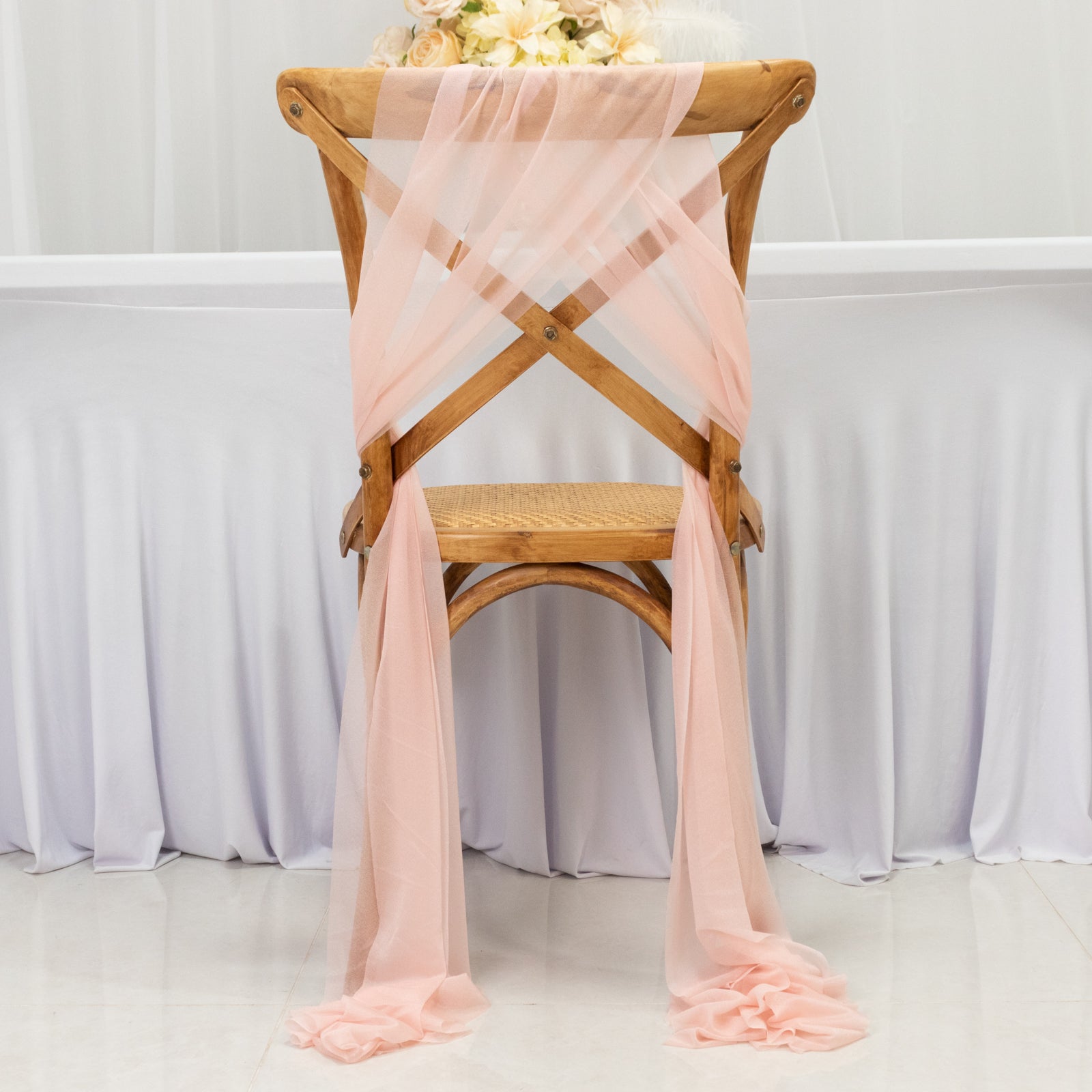 Blush sheer chair drape decor elegantly styled on a wooden chair.