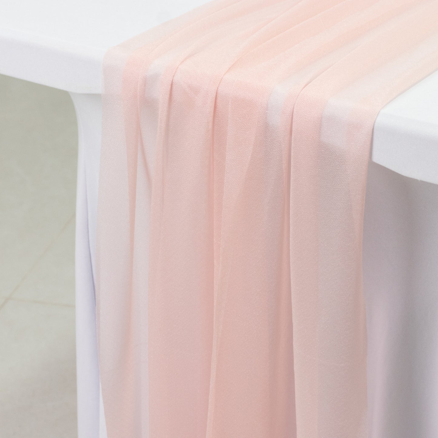 Blush shimmer sheer table runner drapes on a white table.