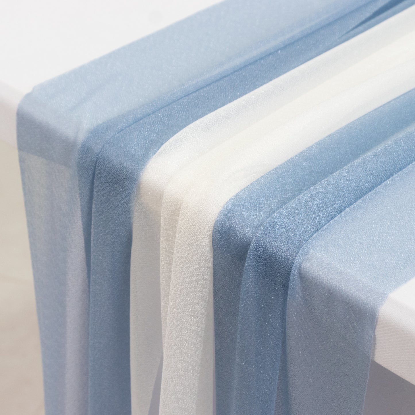 Dusty blue and ivory sheer table runners on a white table.