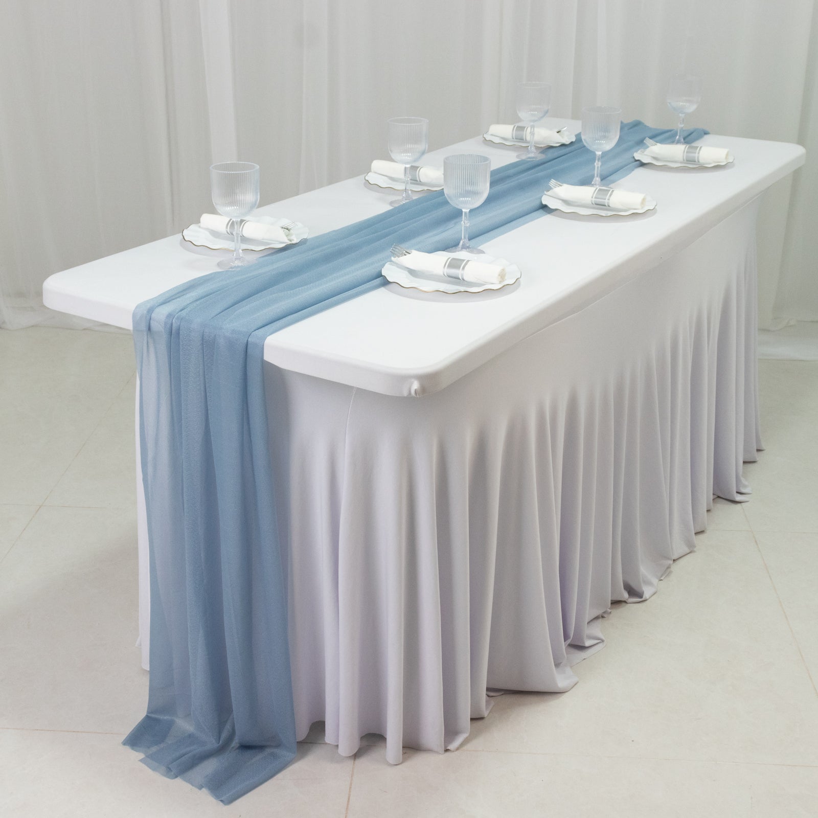 Dusty blue sheer table runners on a white tablecloth.
