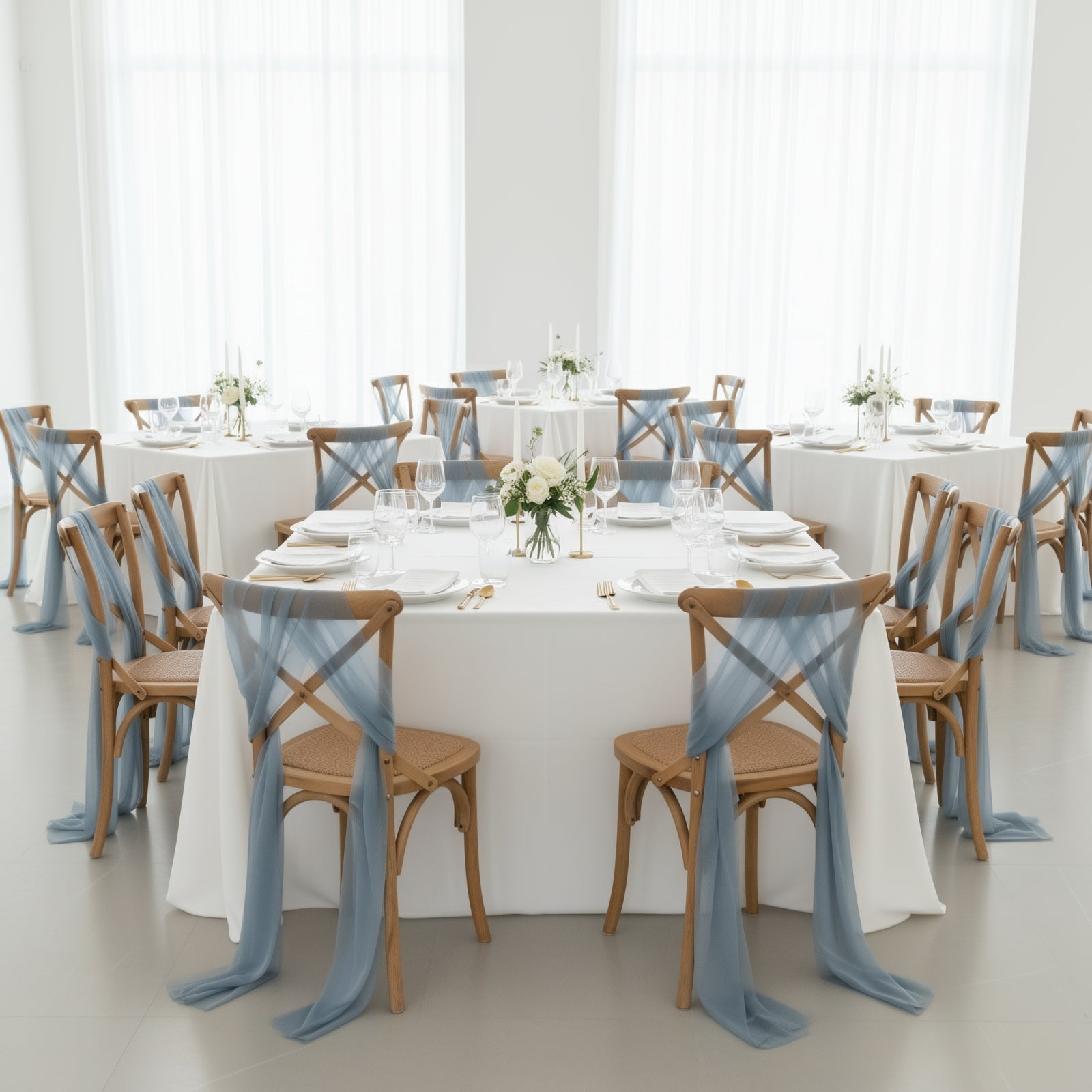 Dusty blue sheer chair drapes on elegant dining chairs in a bright setting.