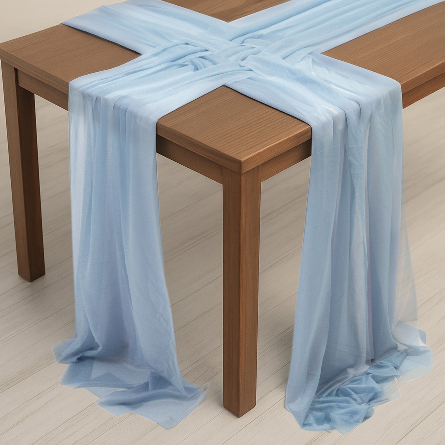 Dusty blue sheer table runners draped elegantly over a wooden table.