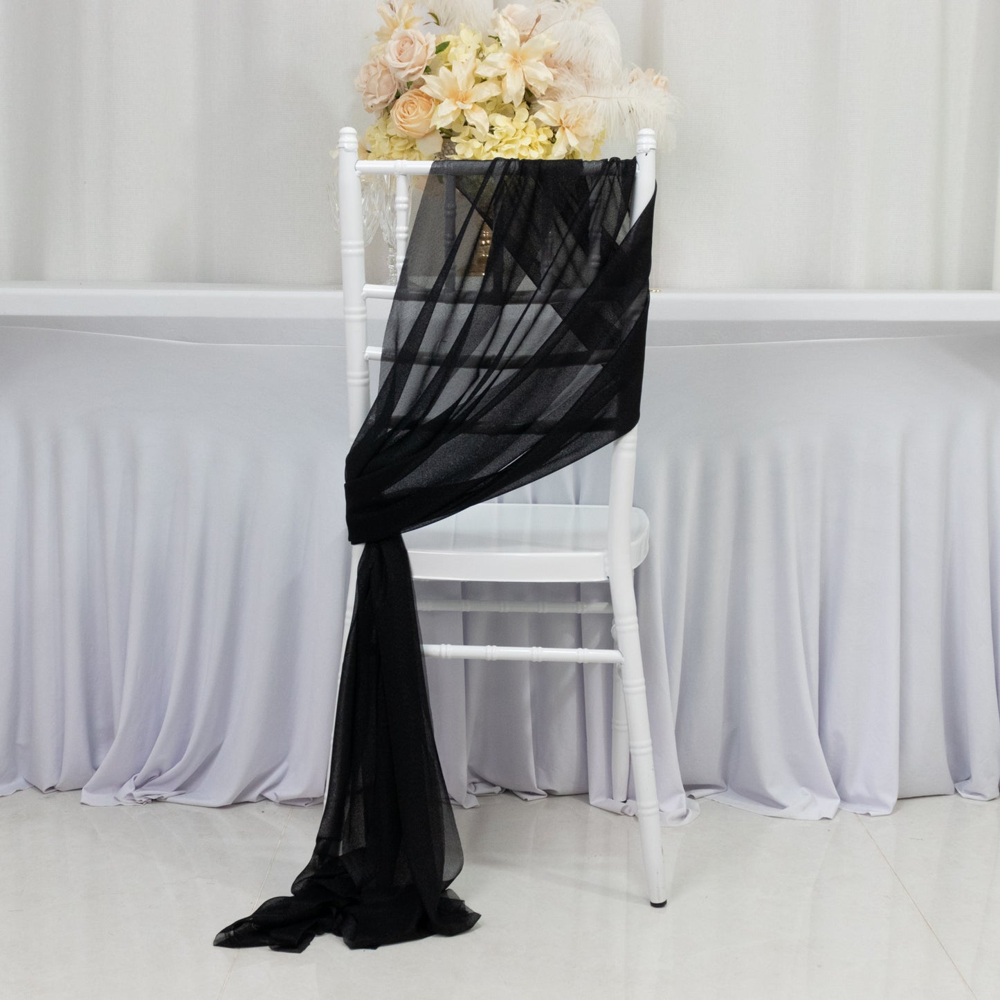 Black sheer chair drape with a shimmer sash, elegantly styled on a white chair.