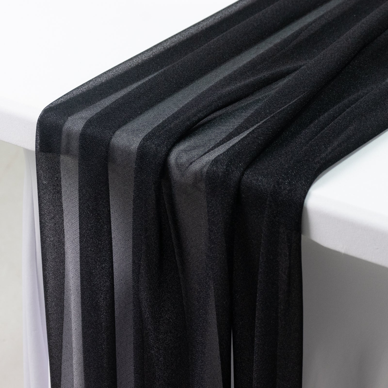 Black shimmer sheer table runners draping over a table.