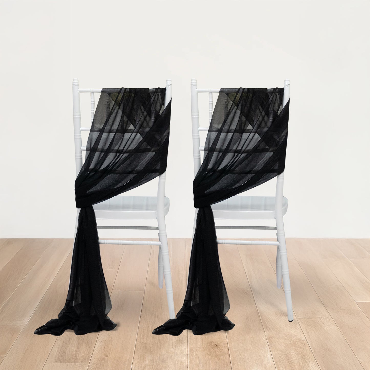 Black sheer chair drape decor on white chairs, featuring a 9ft shimmer sash.