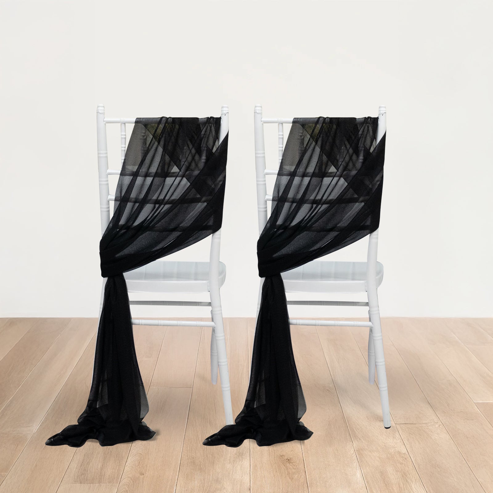 Black sheer chair drape decor on white chairs, featuring a 9ft shimmer sash.