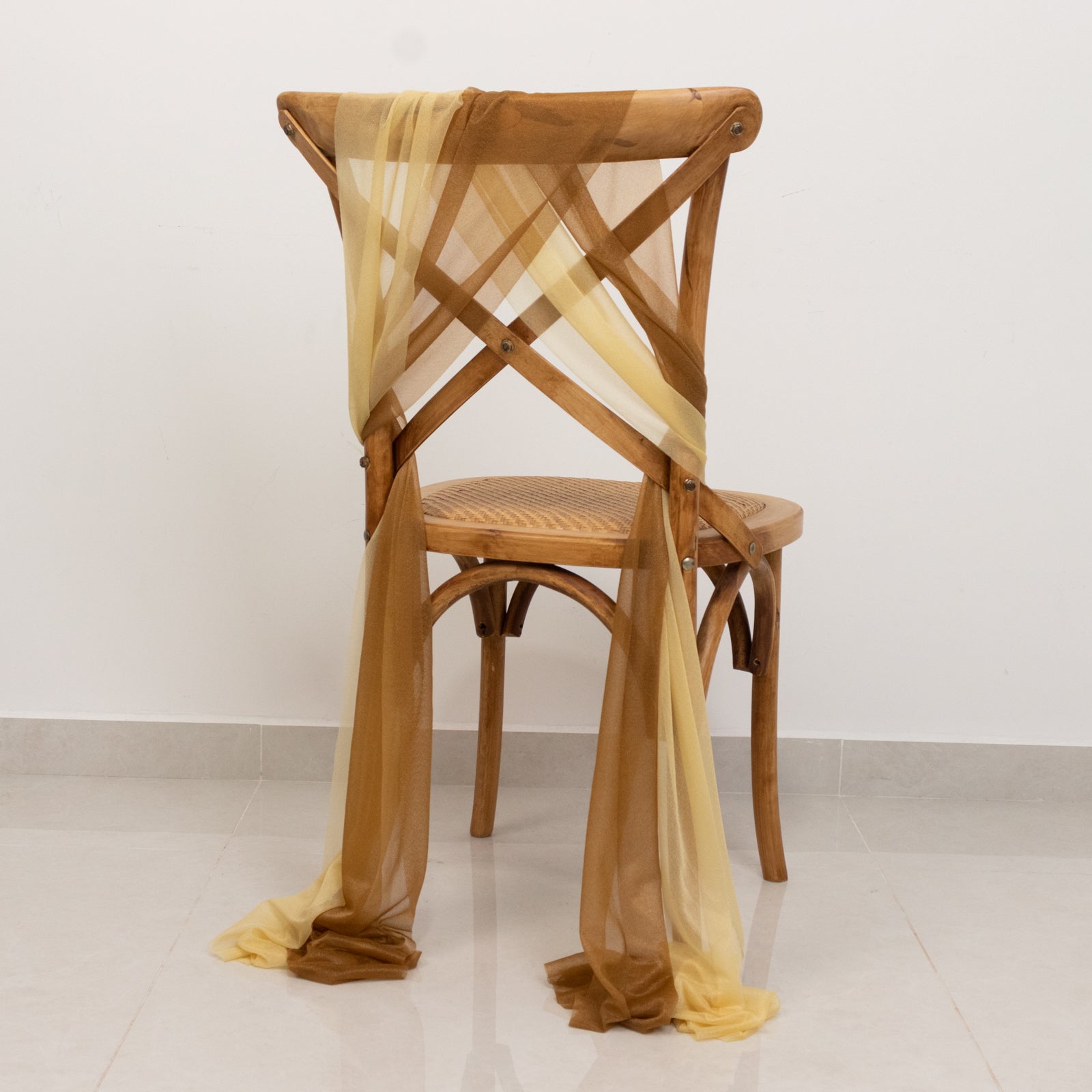 Champagne and gold sheer chair drape decor on a wooden chair.
