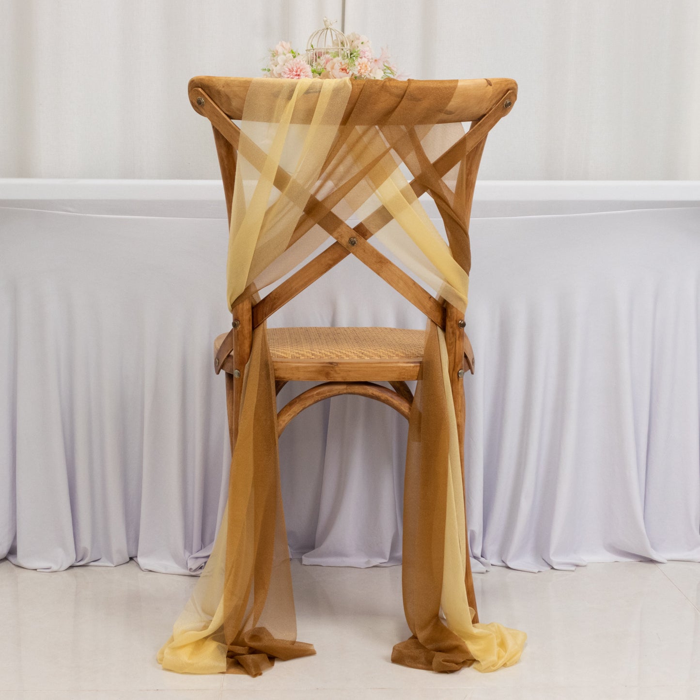 Champagne and gold sheer chair drape decor on a wooden chair.