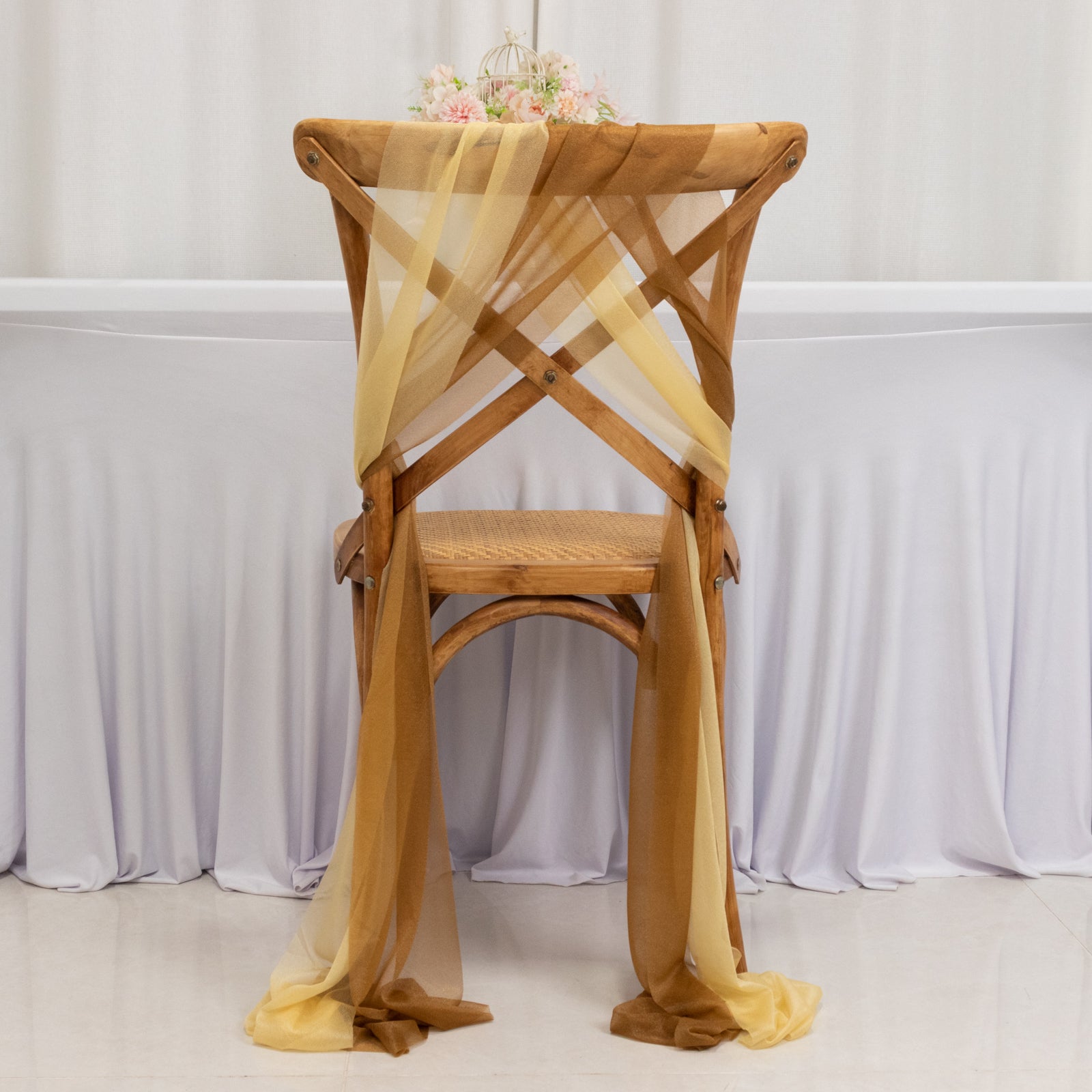 Champagne and gold sheer chair drape decor on a wooden chair.