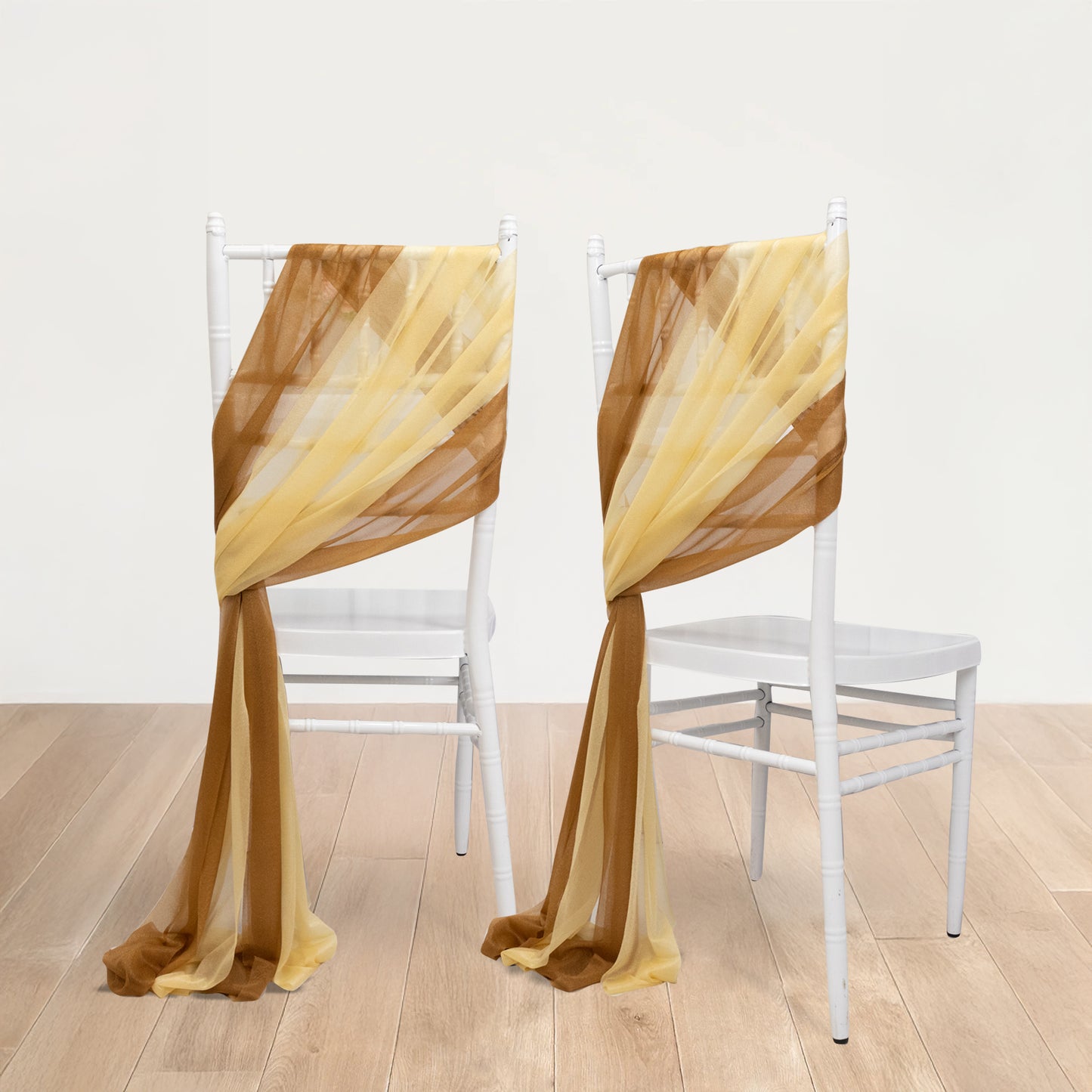 Champagne and gold sheer chair drapes on white chairs.