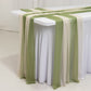 Dusty sage green and beige sheer table runners draped elegantly on a table.