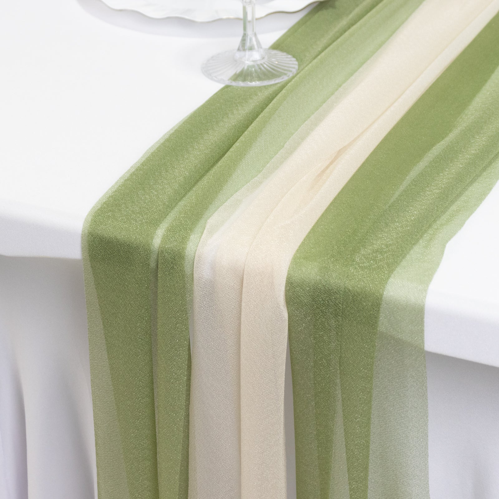 Dusty sage green and beige sheer table runners on a white table.