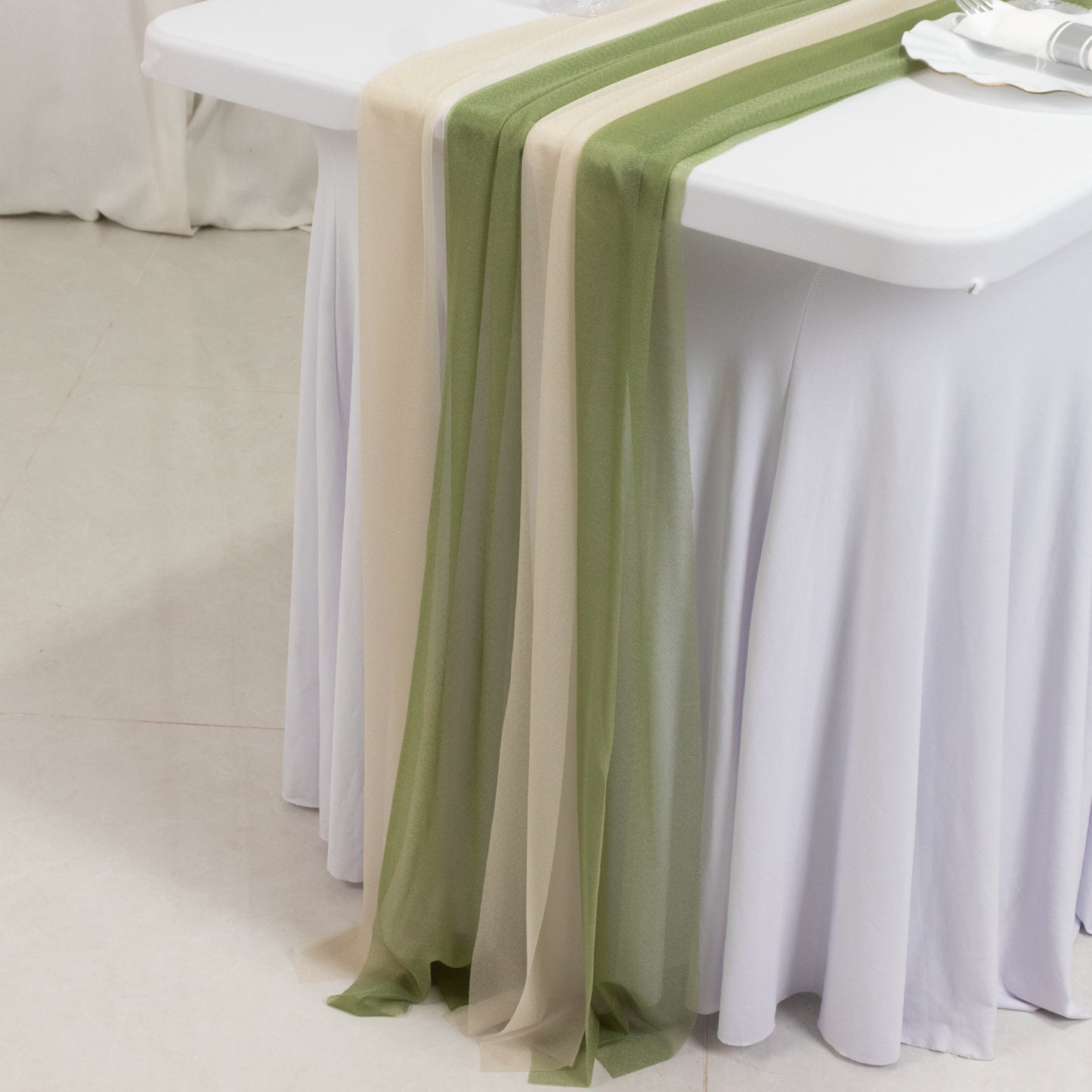 Dusty sage green and beige sheer table runners on a white table.