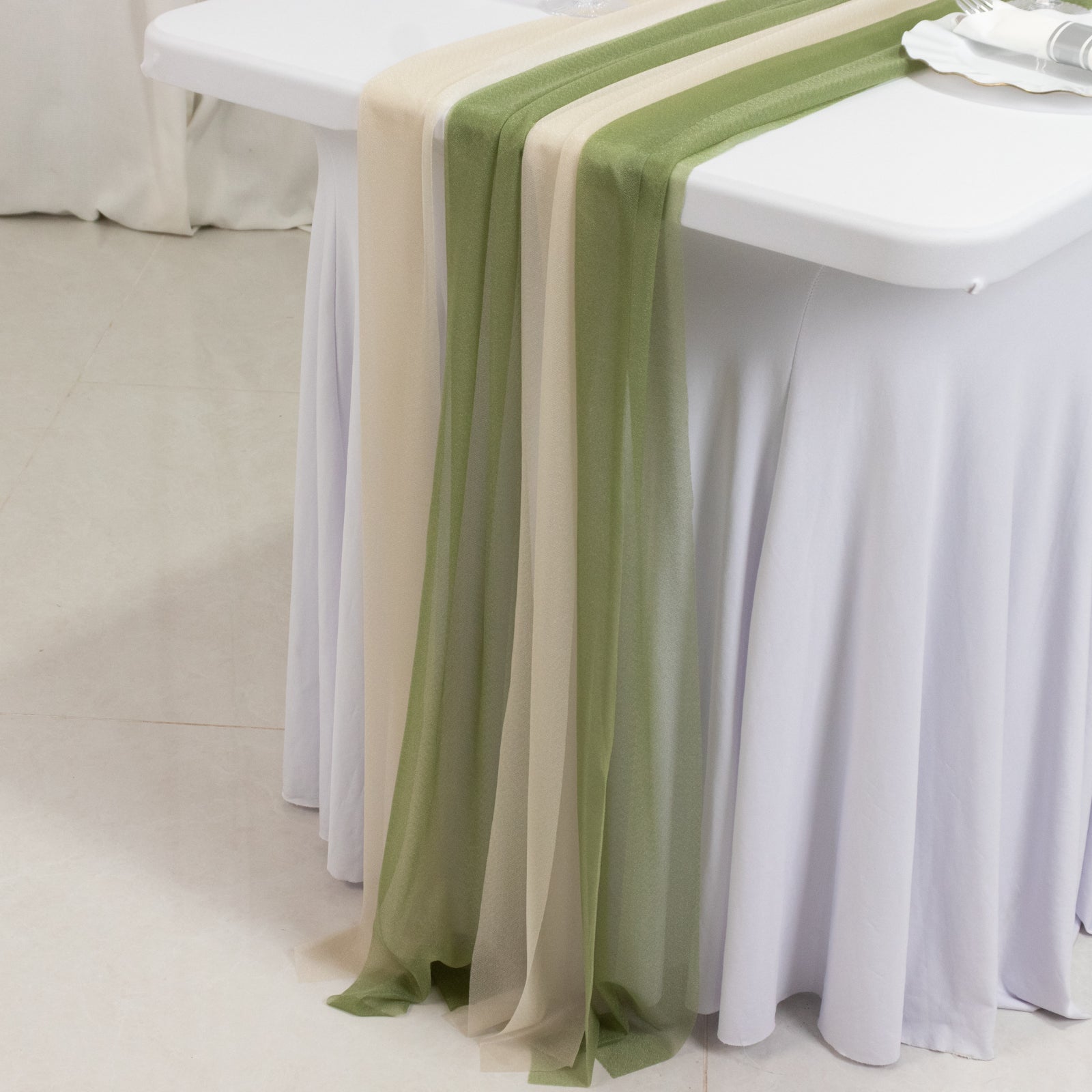 Dusty sage green and beige sheer table runners on a white table.
