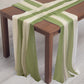 Dusty sage green and beige sheer table runners on a wooden table.