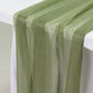 Dusty sage green sheer table runners draped elegantly on a table.