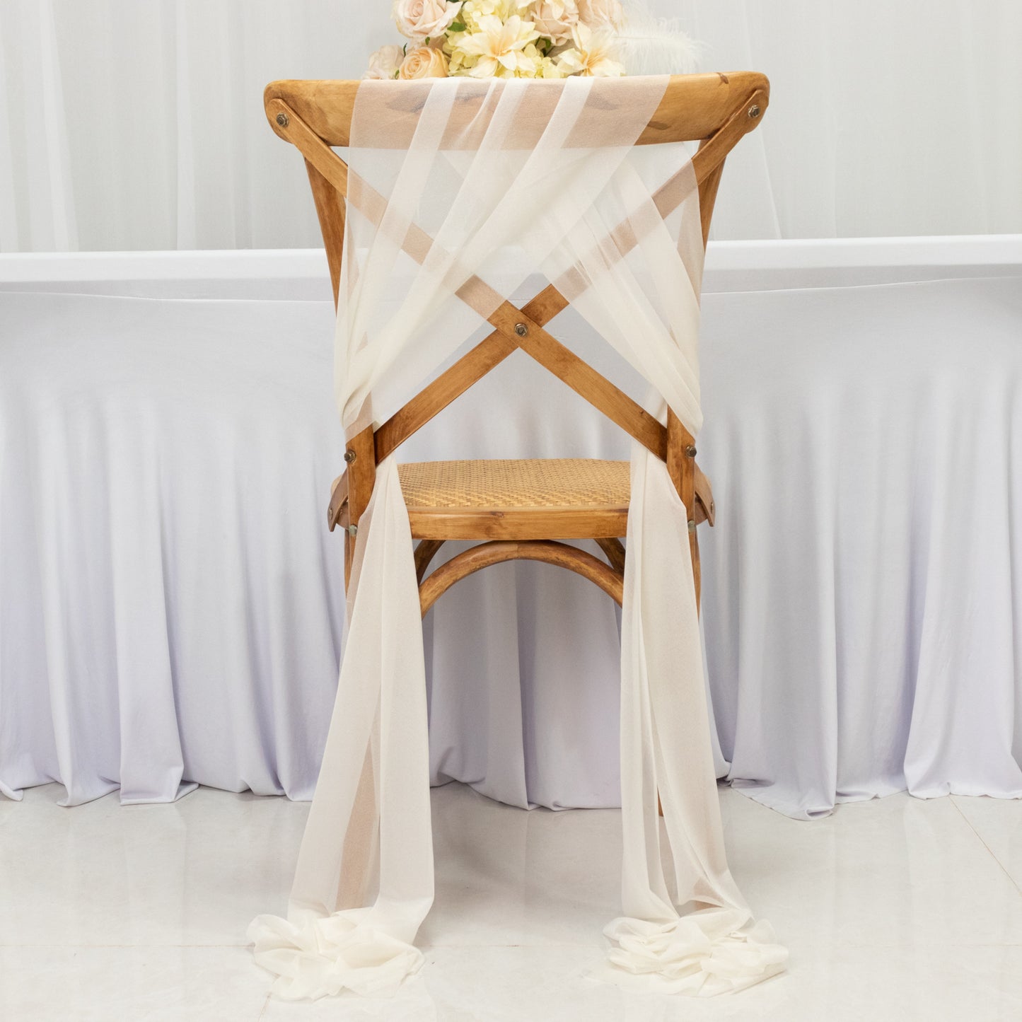 Ivory sheer chair drape with shimmer sash, wrinkle-free decor for events.
