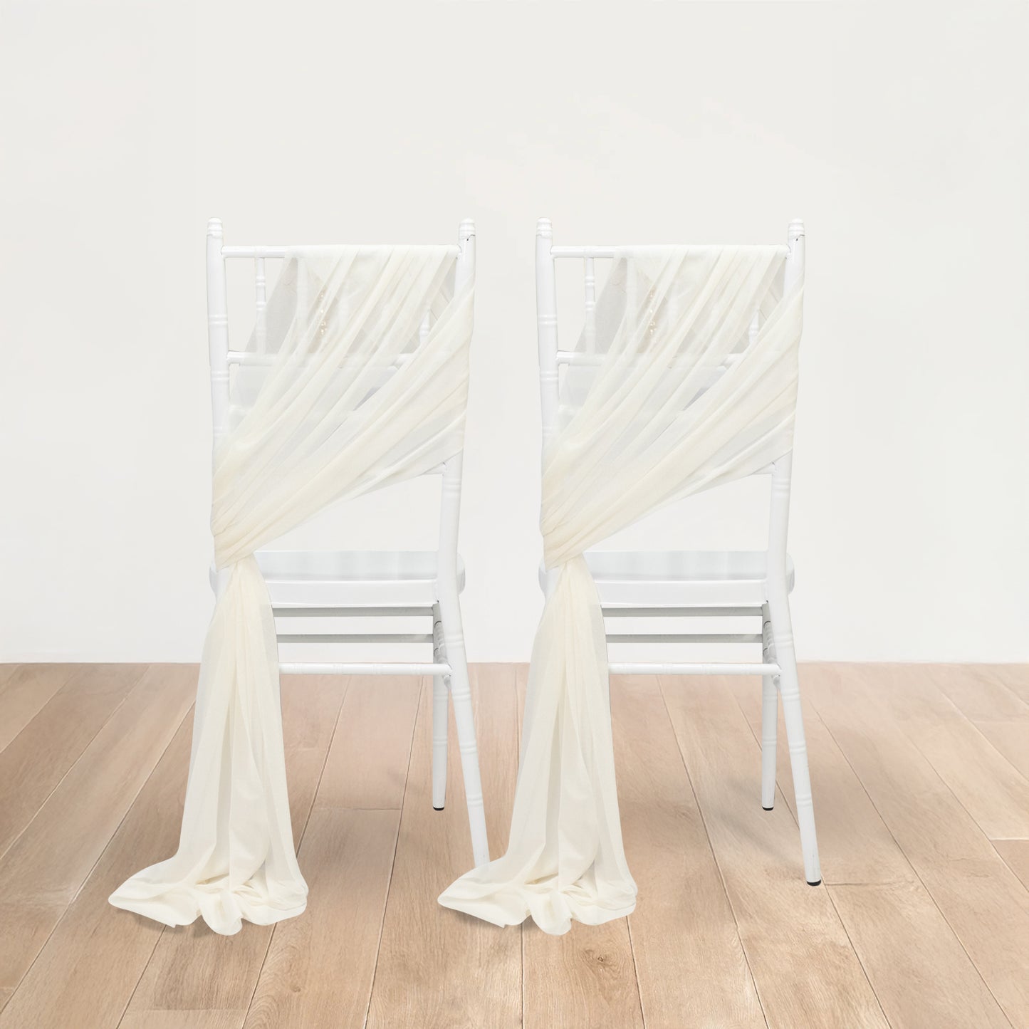 Ivory sheer chair drape decor with shimmer sash on white chairs.