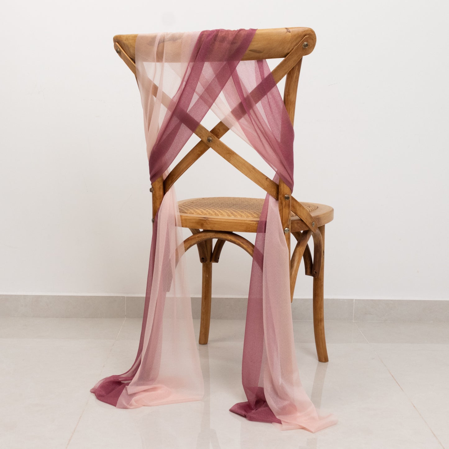 Mauve and blush sheer chair drapes on a wooden chair.