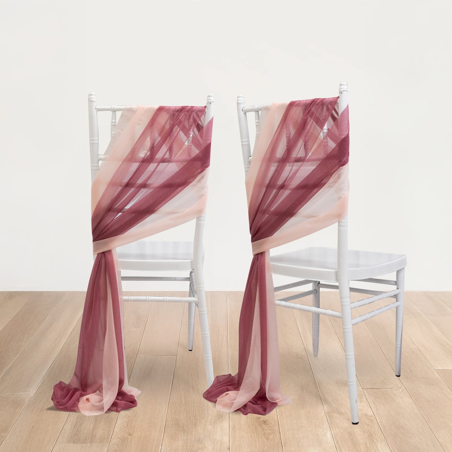 Mauve and blush sheer chair drapes on white chairs.
