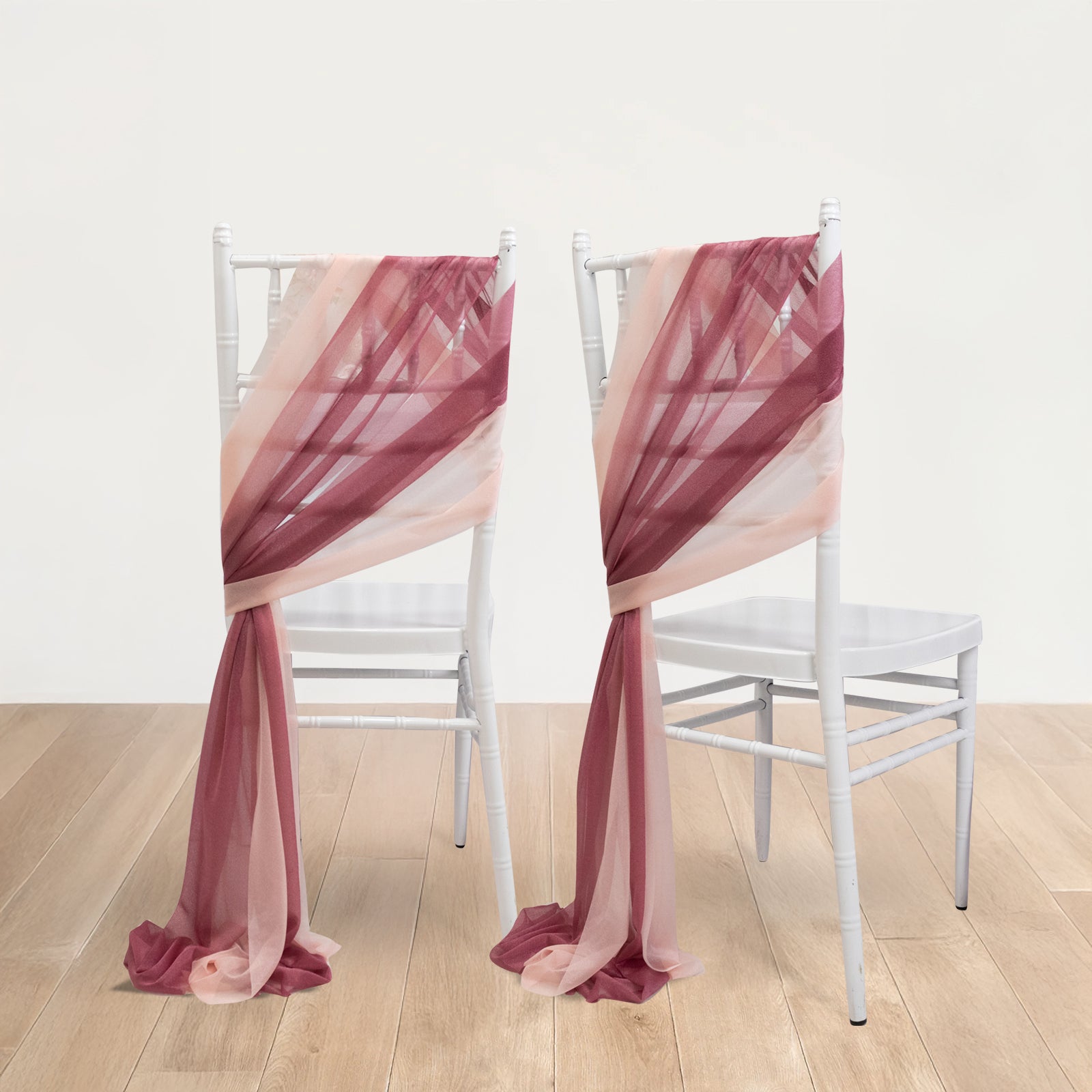 Mauve and blush sheer chair drapes on white chairs.