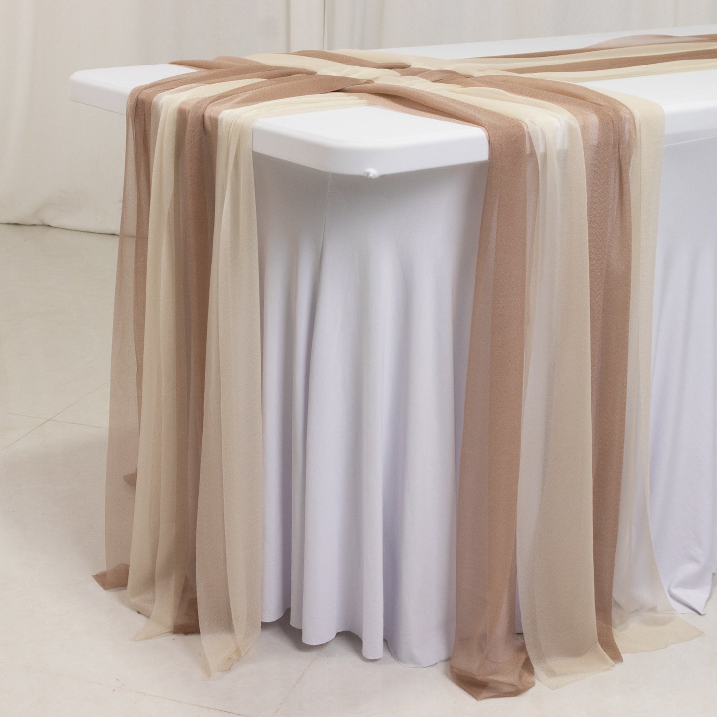 Taupe and beige sheer table runners draping over a white table.