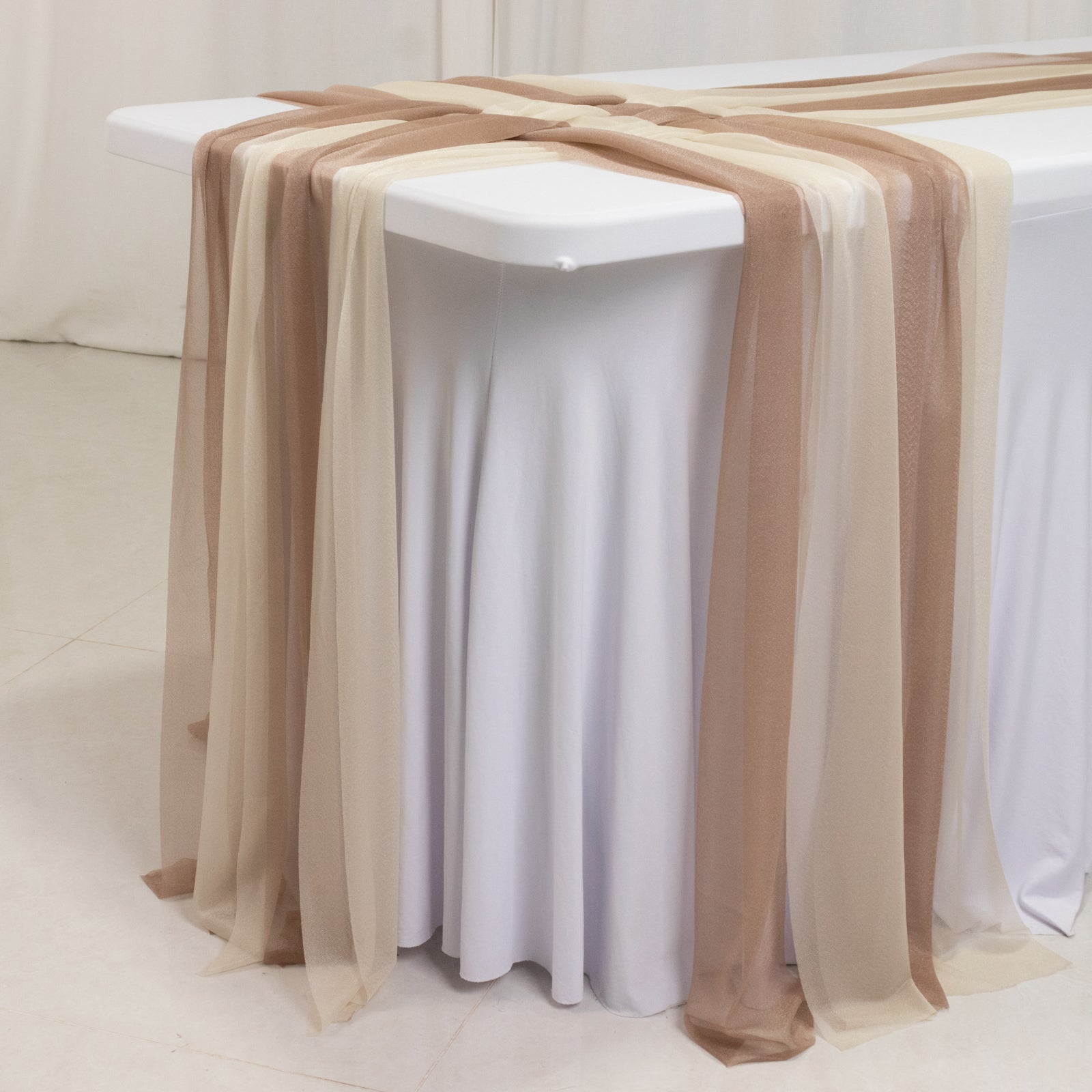 Taupe and beige sheer table runners draping over a white table.