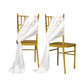 White sheer chair drapes on gold chairs, creating an elegant decor.